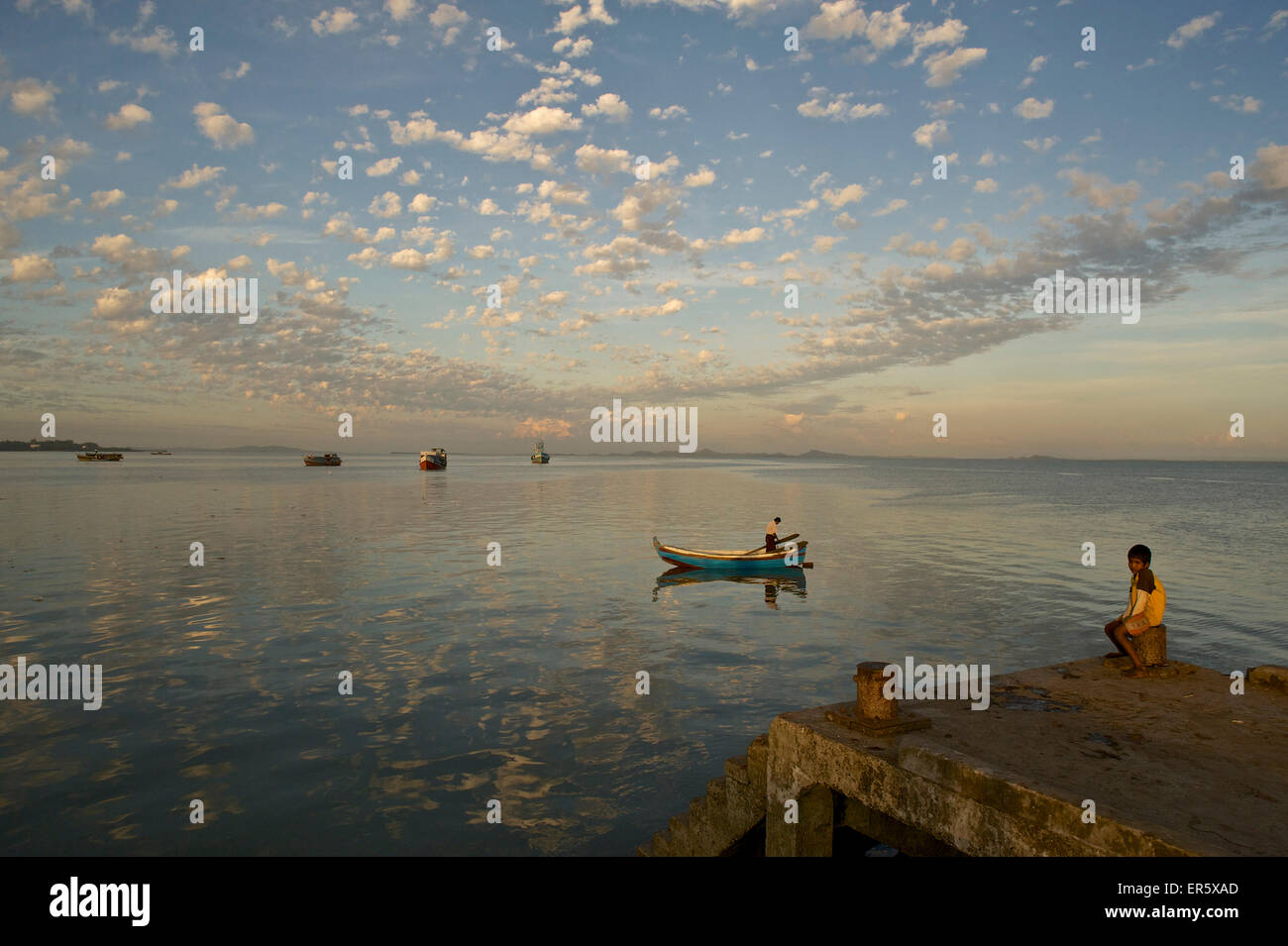 Kind sitzt auf dem Pier, Sittwe, Akyab, Fischerboot mit einigen Fischern im Hafen, Rakhaing-Staat Arakan, Myanmar, Stockfoto