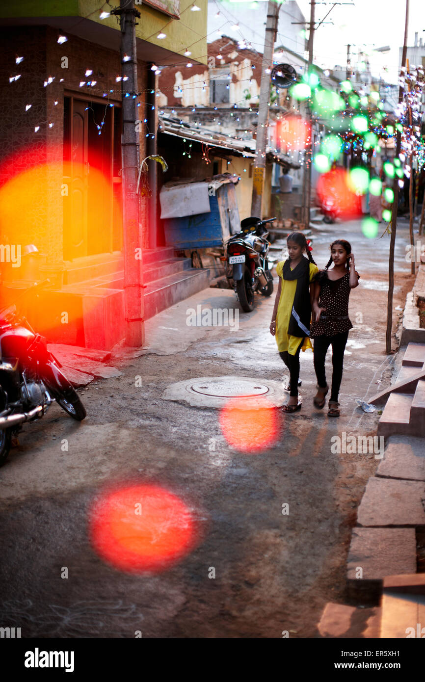 Mädchen zu Fuß entlang einer Straße geschmückt mit Lichterketten, Mysore, Karnataka, Indien Stockfoto