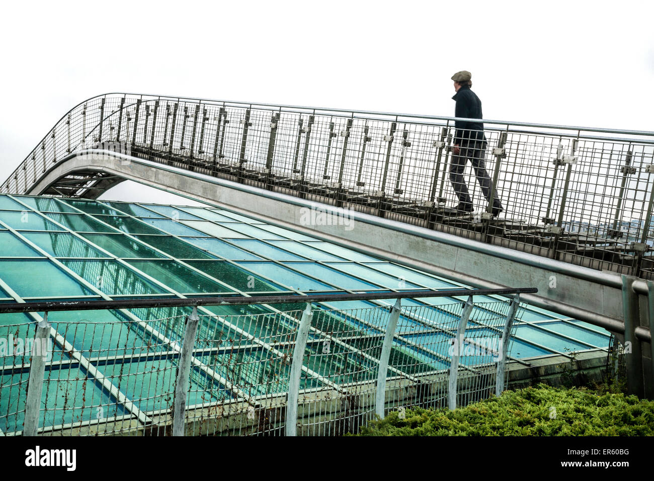 Mann steigt eine Metallbrücke über ein Glasdach in der Universitätsbibliothek Warschau Garten, entworfen von Irena Bajerska Stockfoto