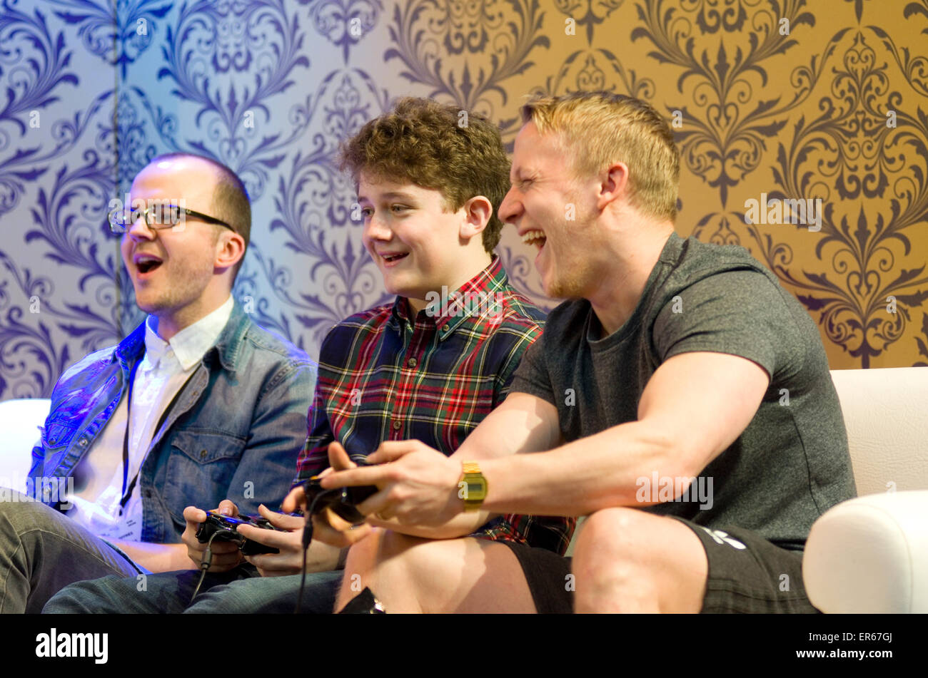 Drei Männer, die Spaß und lachen beim Spielen von Computerspielen auf einem Sofa. Stockfoto