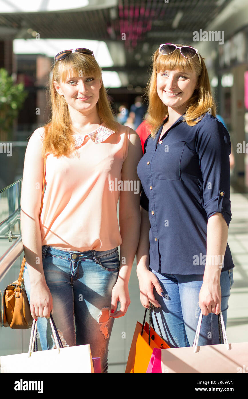Junge Zwillinge Mädchen viel Spaß halten ihre Einkaufstüten. Zwei kaukasischen Schwestern lächelnd in der Shopping mall Stockfoto