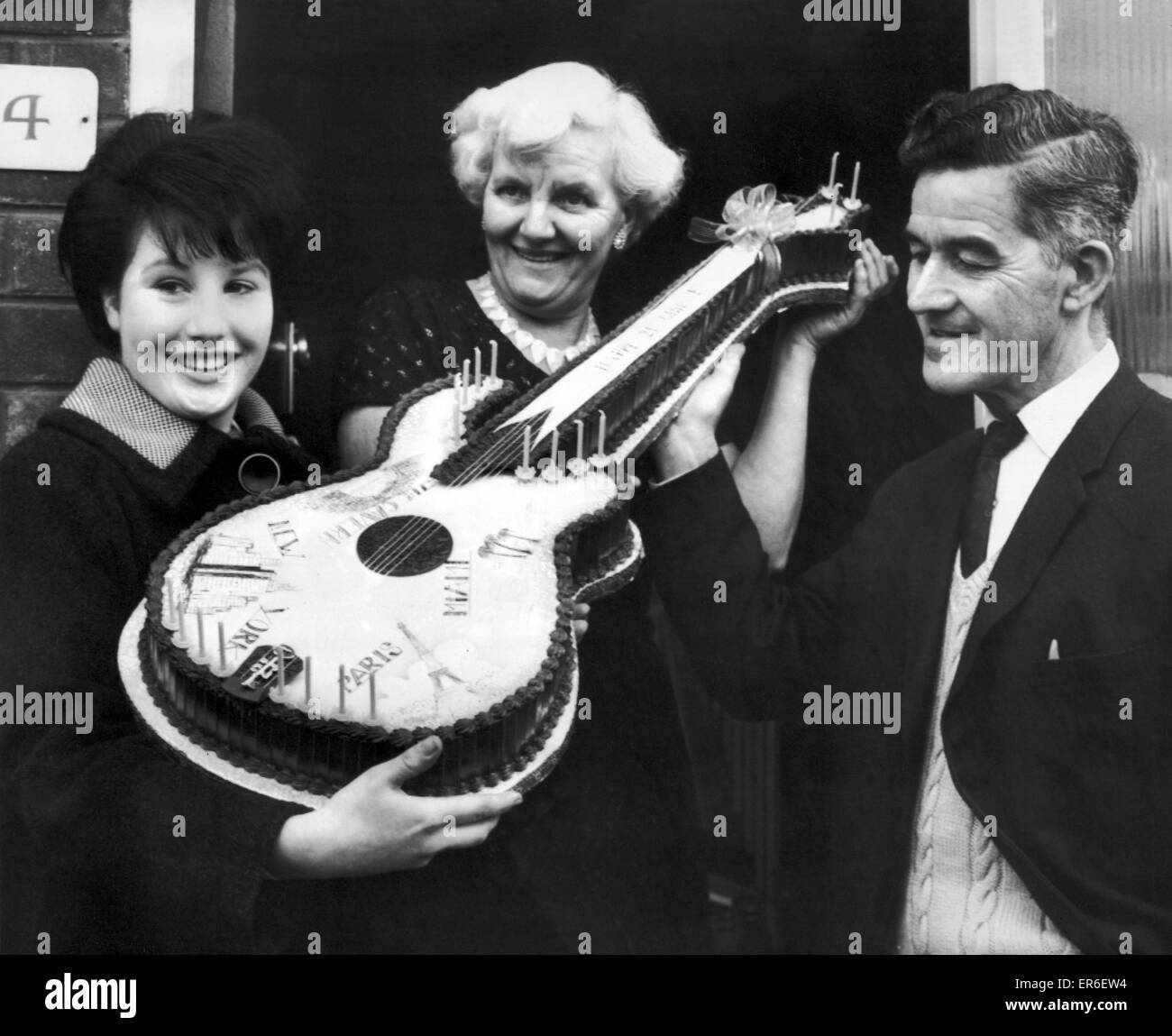 Beatles-Fan, Jeanette Vertrauen 16 aus West Derby, Liverpool, präsentiert Harold und Louise Harrison, Eltern von George Harrison, mit einer Geburtstagstorte in Form einer Gitarre, die sie dazu beigetragen, dass seinen 21. Geburtstag feiern. Bild 25. Februar 1964. Stockfoto