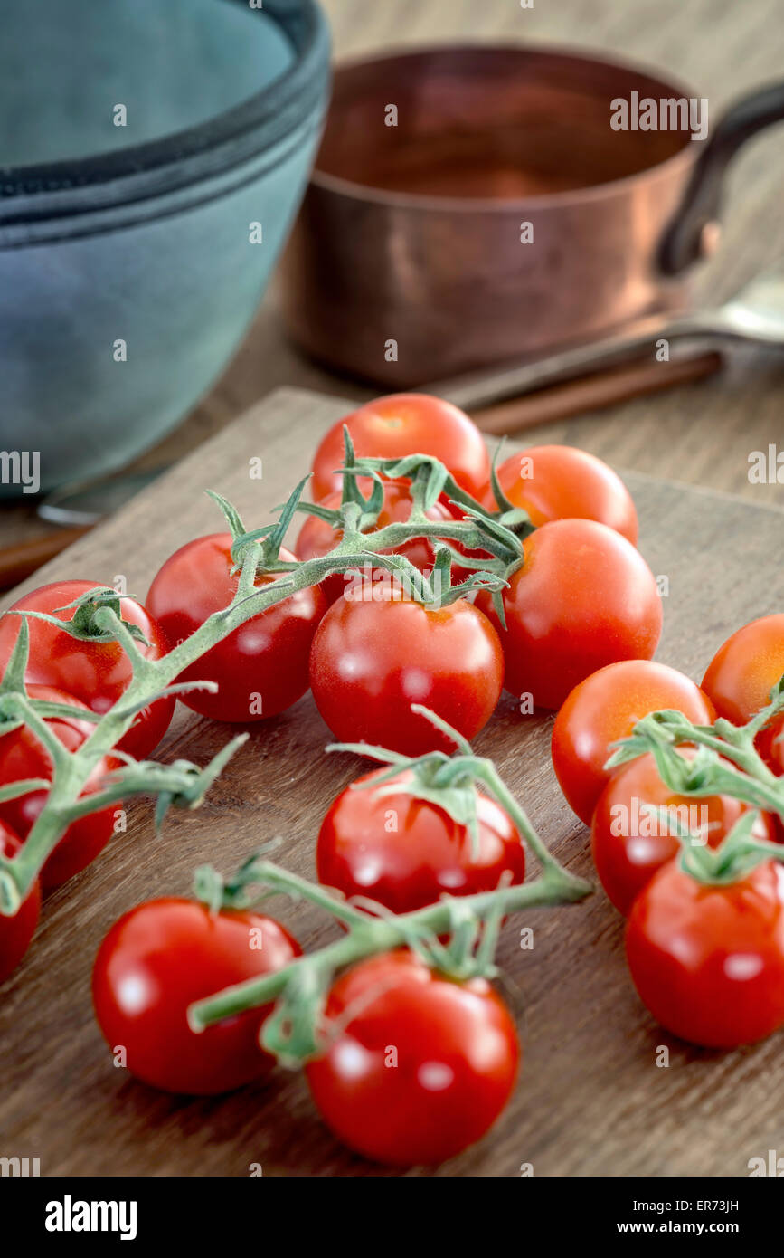 Einige Reben gereifter Tomaten auf Schneidebrett. Stockfoto