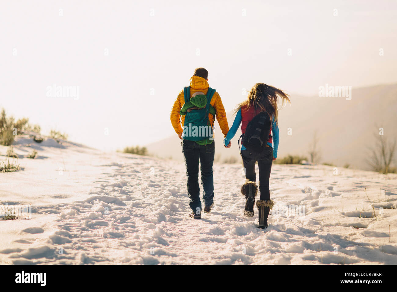 Ein junges Paar hält Hände und Wanderungen gegen einen Winter-Berg-Szene und leuchtenden Sonnenuntergang. Stockfoto