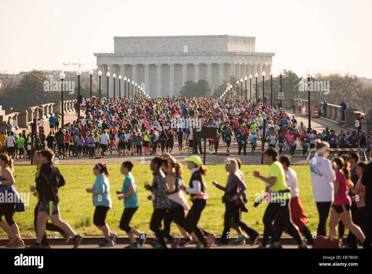 WASHINGTON DC, USA – die Läufer des Credit Union Cherry Blossom 10 Mile Run von 2015 fahren über die Arlington Memorial Bridge, mit dem Lincoln Memorial im Hintergrund. Der Cherry Blossom 10-Miler (ehemals Credit Union Cherry Blossom 10 Mile Run) findet jedes Frühjahr während des National Cherry Blossom Festival statt und zieht Tausende von Läufern an. Stockfoto