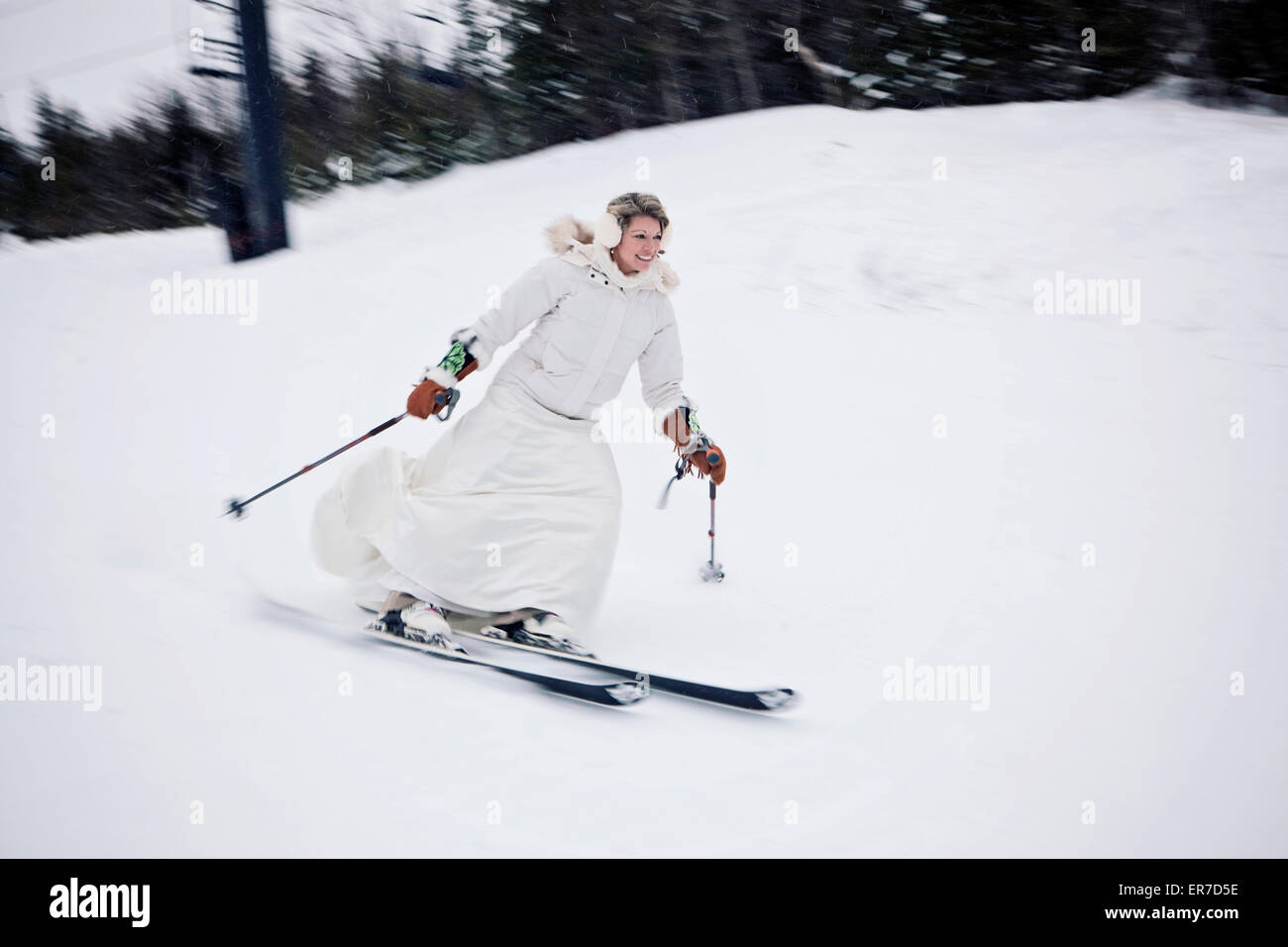 Eine Frau Ski einen Berg hinunter in ein Brautkleid nach der Hochzeit. Stockfoto