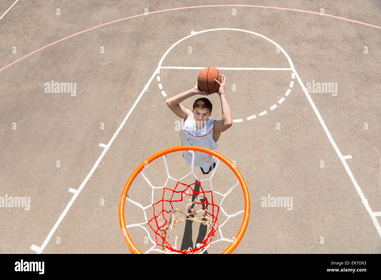 High Angle View von Rückwand des athletischen Jünglings machen Sprungwurf Netz auf Outdoor-Basketball-Platz Stockfoto