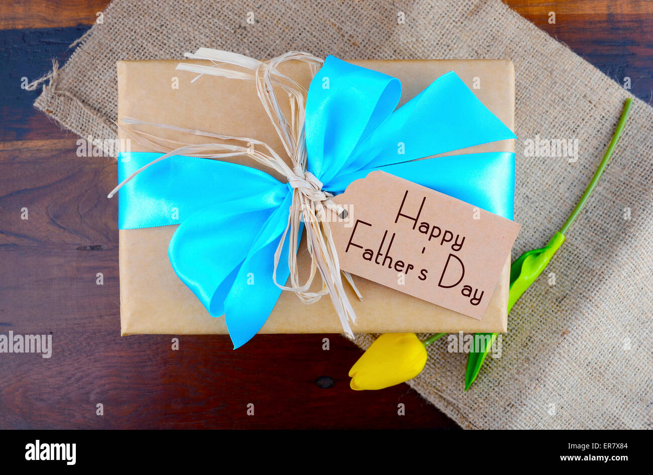 Happy Fathers Day natürliche Kraftpapier umwickelt Owith blass blau Geschenkband auf dunklem Holz. Stockfoto