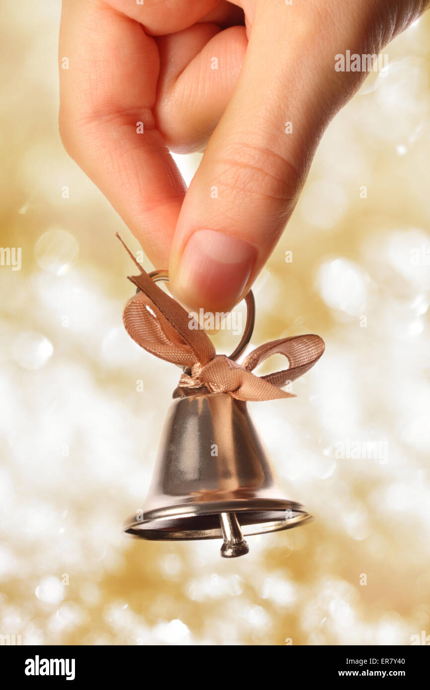 Glocke in weiblicher Hand Closeup auf Funkeln Hintergrund Stockfoto