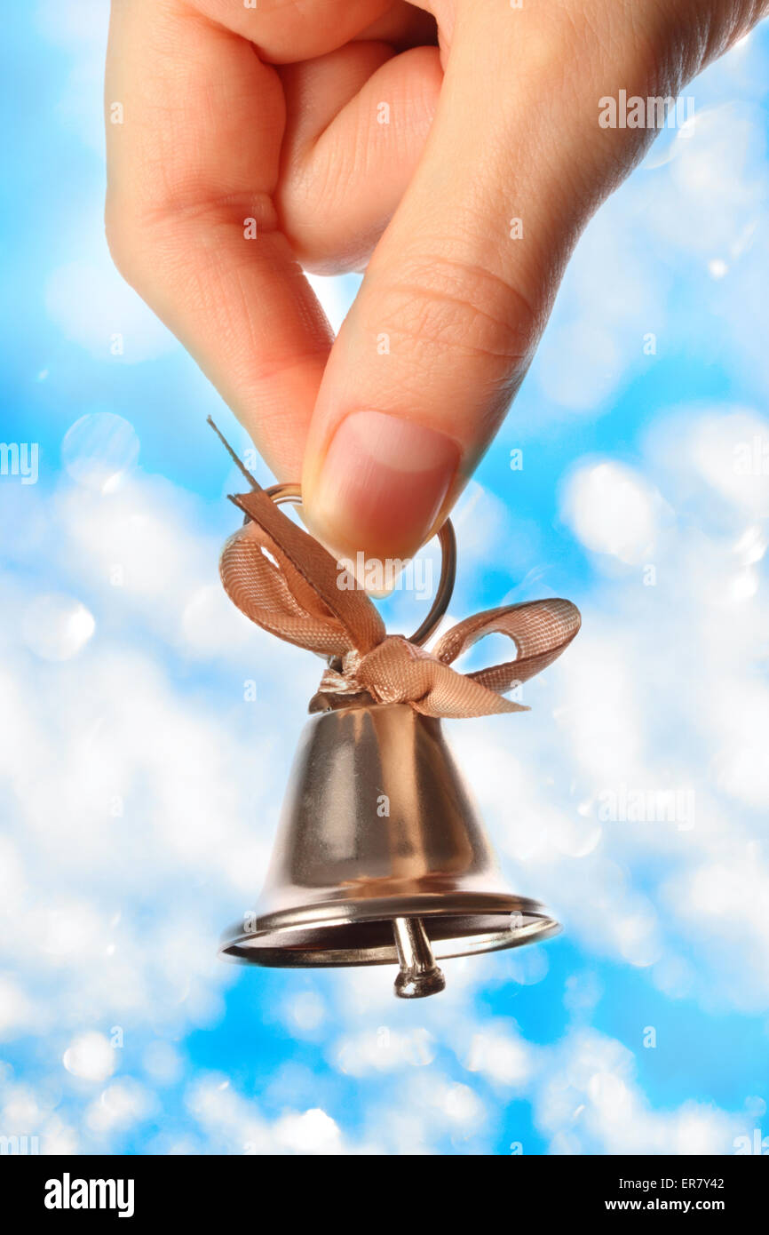Glocke in weiblicher Hand Closeup auf Funkeln Hintergrund Stockfoto