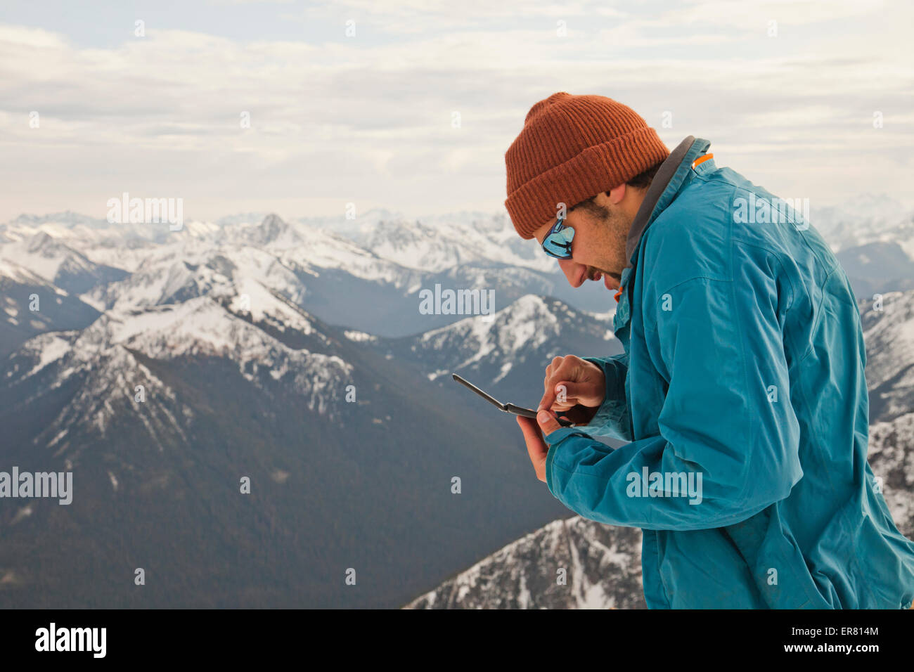 Ein Wanderer prüft seine SMS-Nachrichten auf dem Gipfel eines Berges. Stockfoto