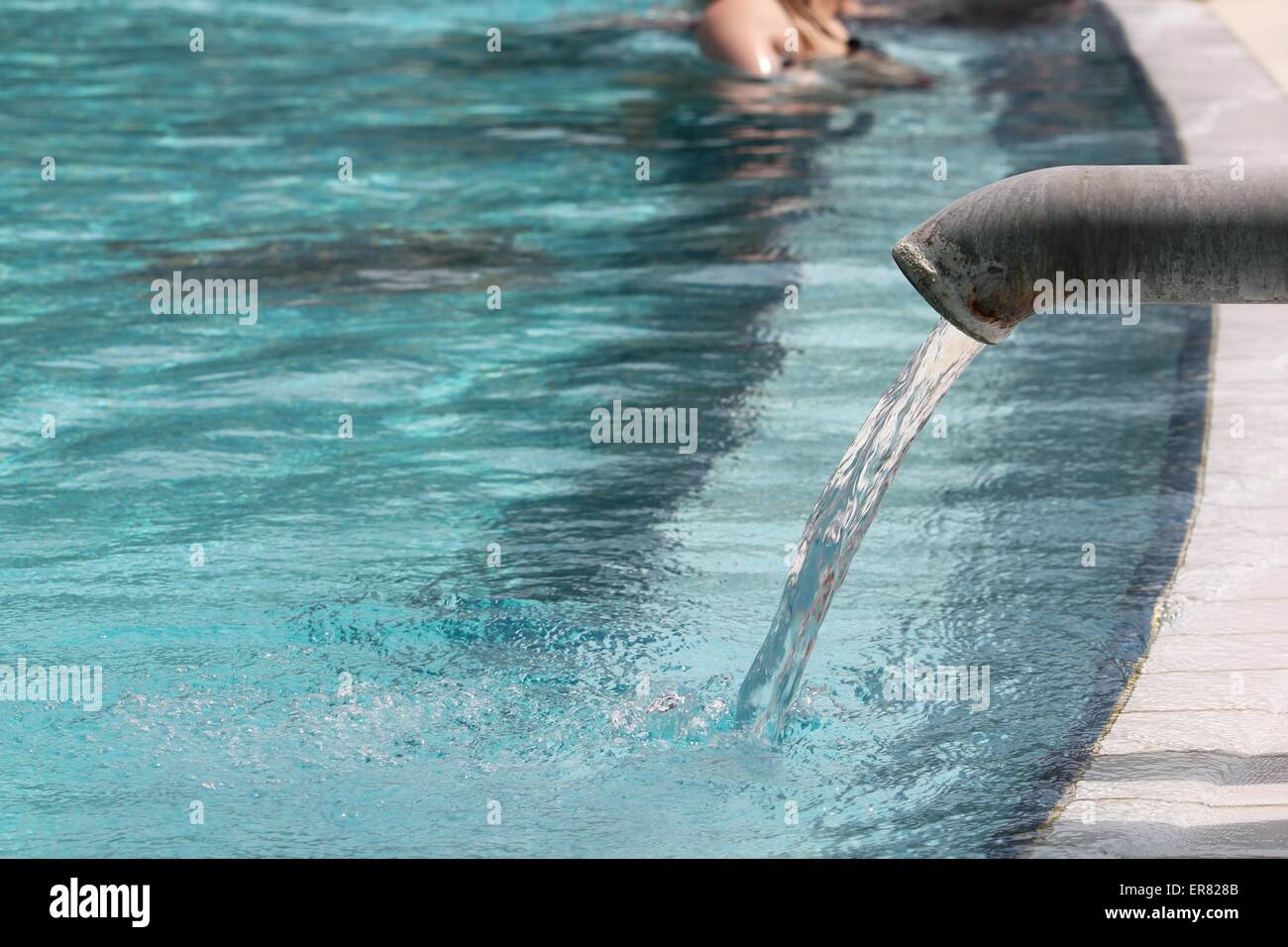 heißes Thermalwasser fließt in ein Hotel-Pool aus einem Metall Hahn, Spa-Hintergrund Stockfoto