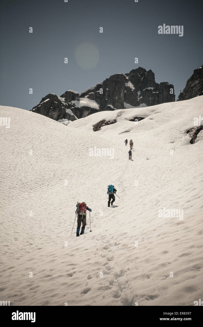 Sechs Bergsteiger überqueren einen Schnee-Patch auf dem Weg, um Klettern Trio Berg in British Columbia, Kanada. Stockfoto
