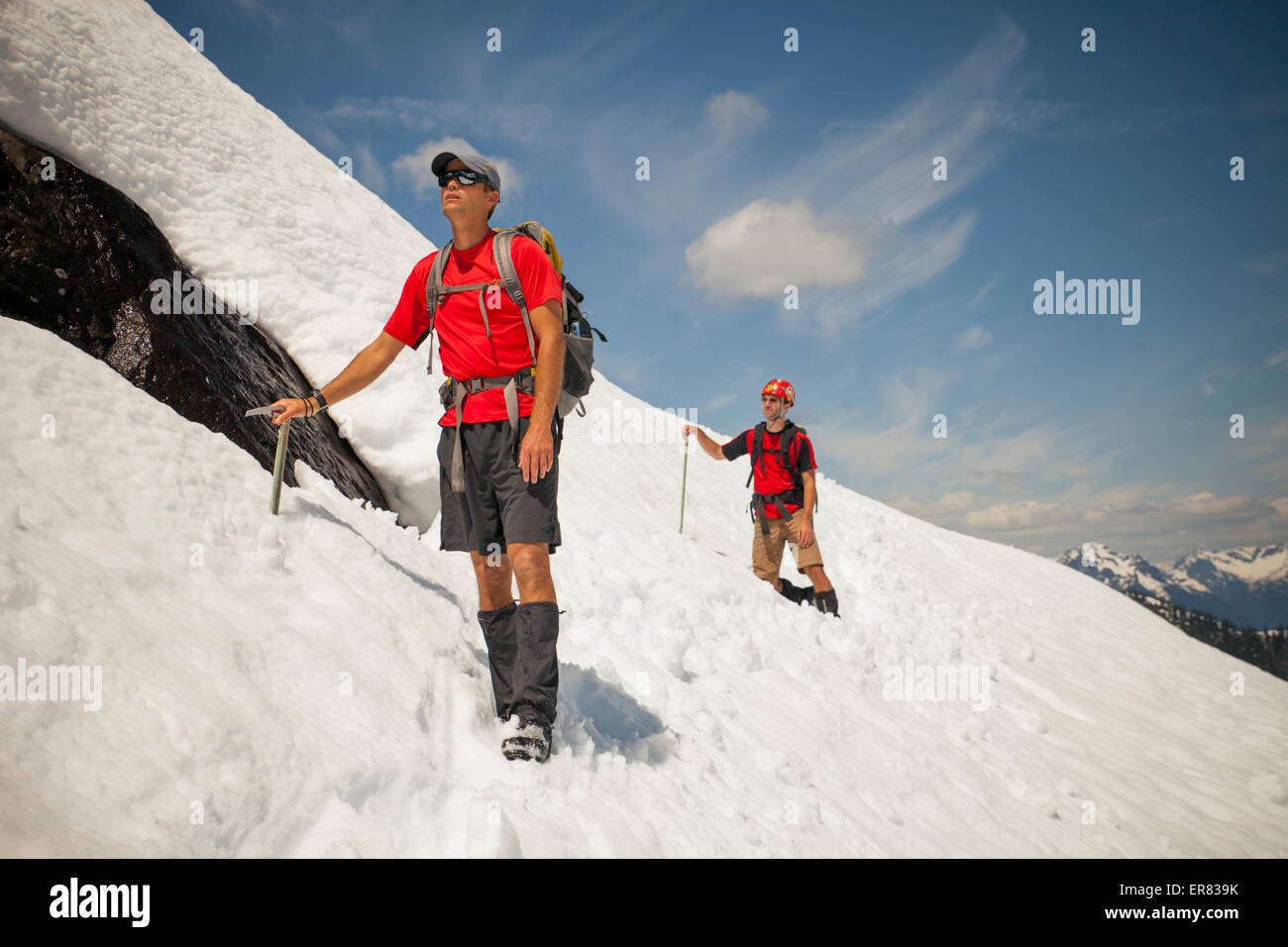 Zwei Bergsteiger Kreuz ein Schneefeld hoch in den Bergen. Stockfoto