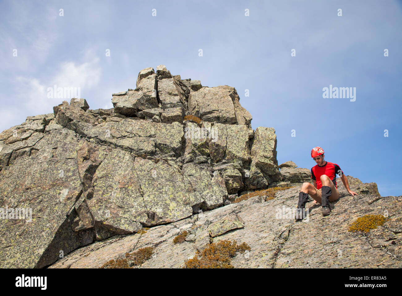 Ein Bergsteiger hinunter klettert einen felsigen Gipfel. Stockfoto