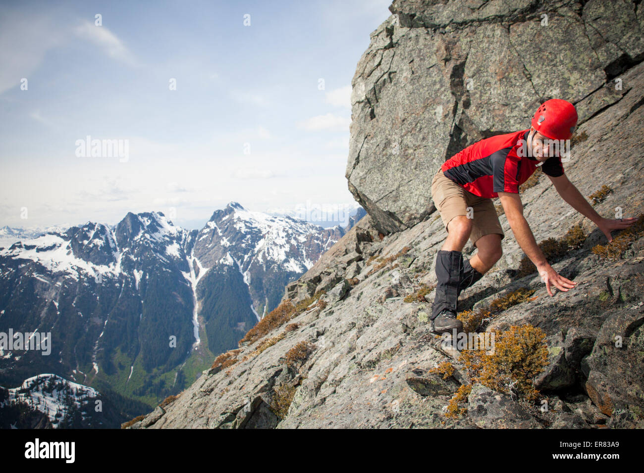 Ein Bergsteiger kreuzt sorgfältig eine steile Felsplatte nahe dem Gipfel des Trio Peak Stockfoto