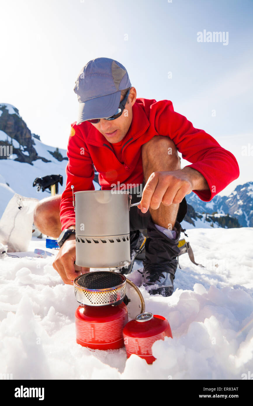 Ein Bergsteiger verwendet einen Campingkocher, um sein Abendessen zu machen. Stockfoto