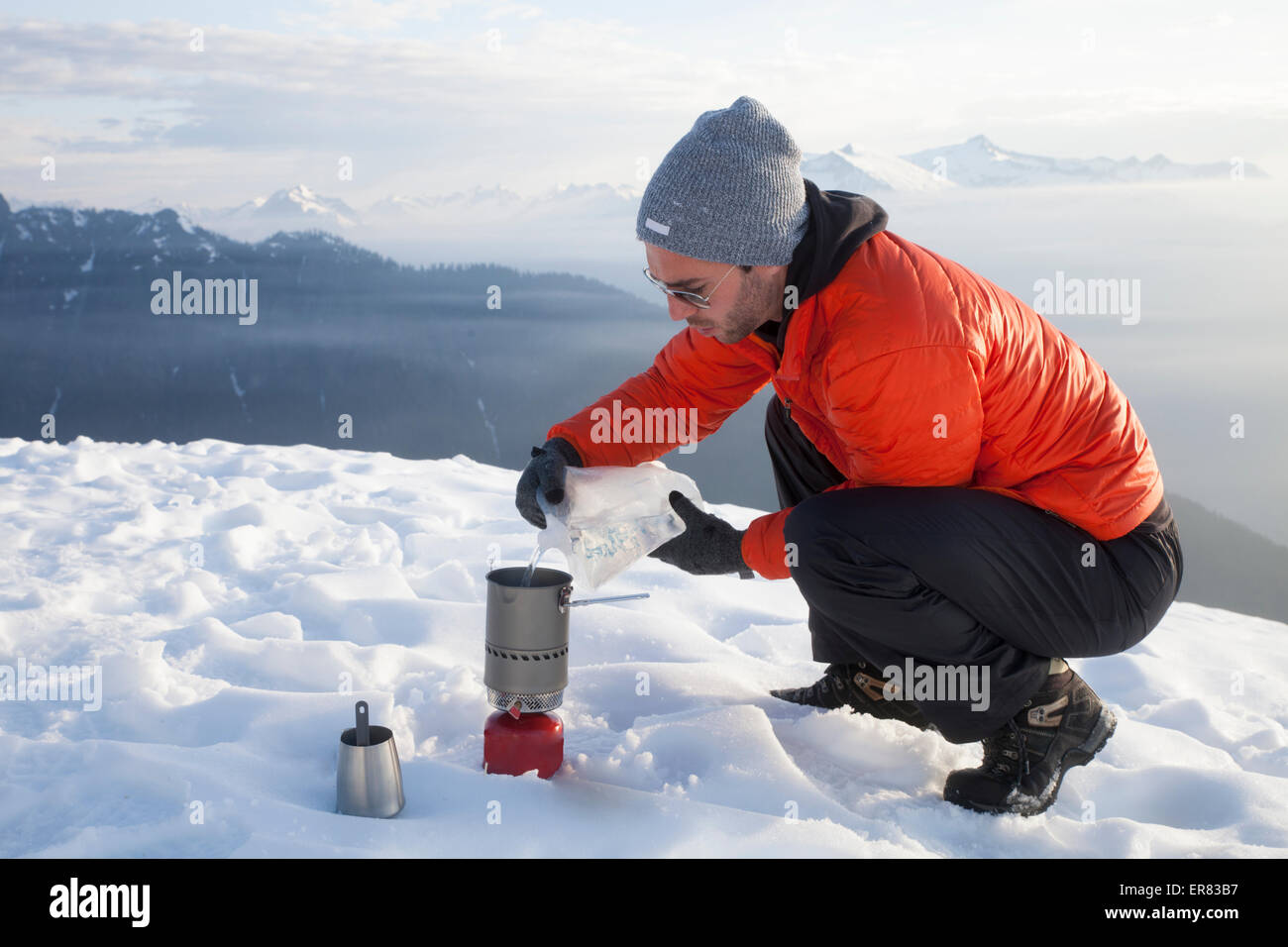 Ein Bergsteiger gießt Wasser in einem Campingkocher beim camping in den Bergen. Stockfoto