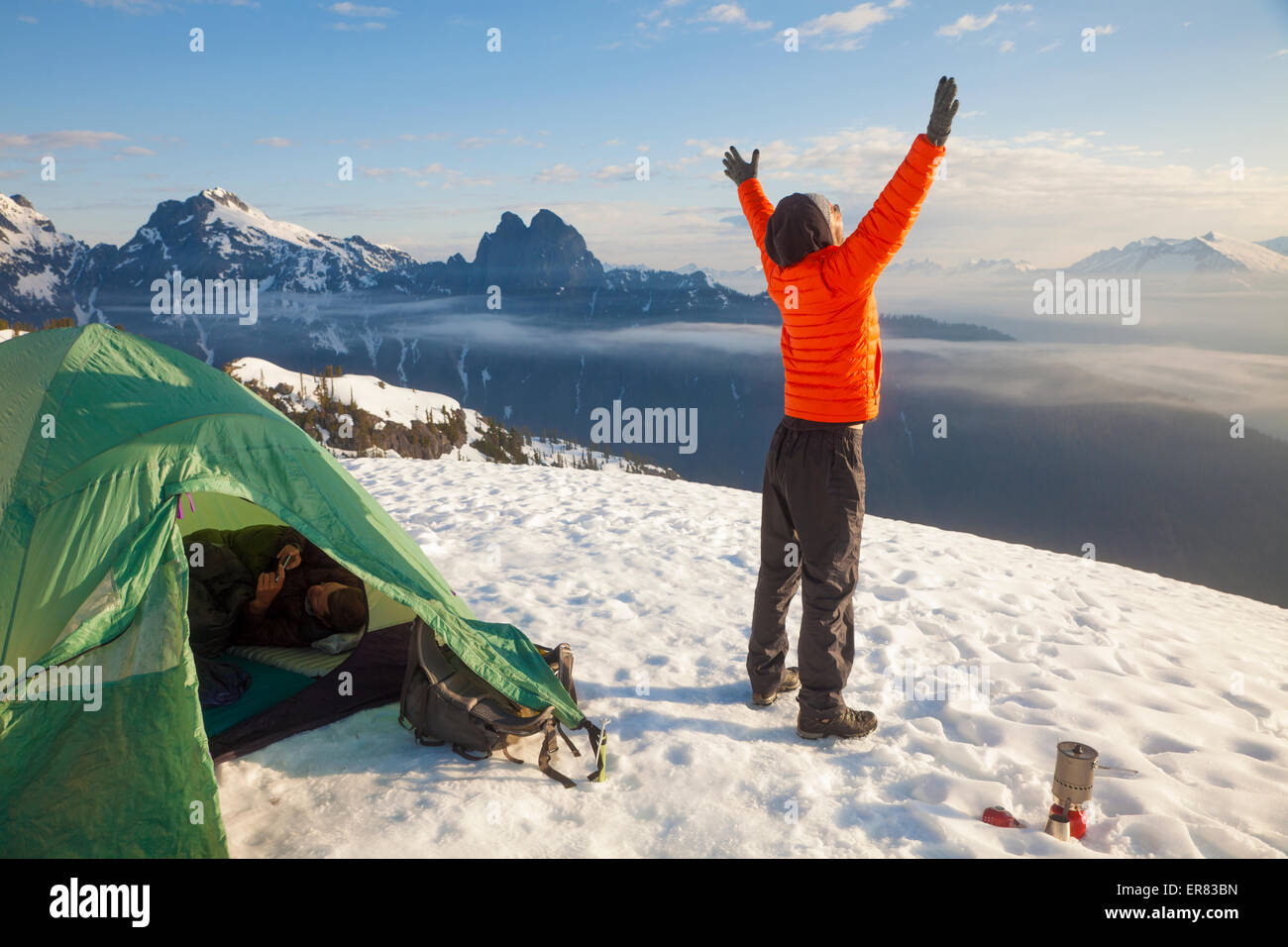 Ein Bergsteiger feiert den schönen Tag wachte er bis beim camping in den Bergen. Stockfoto