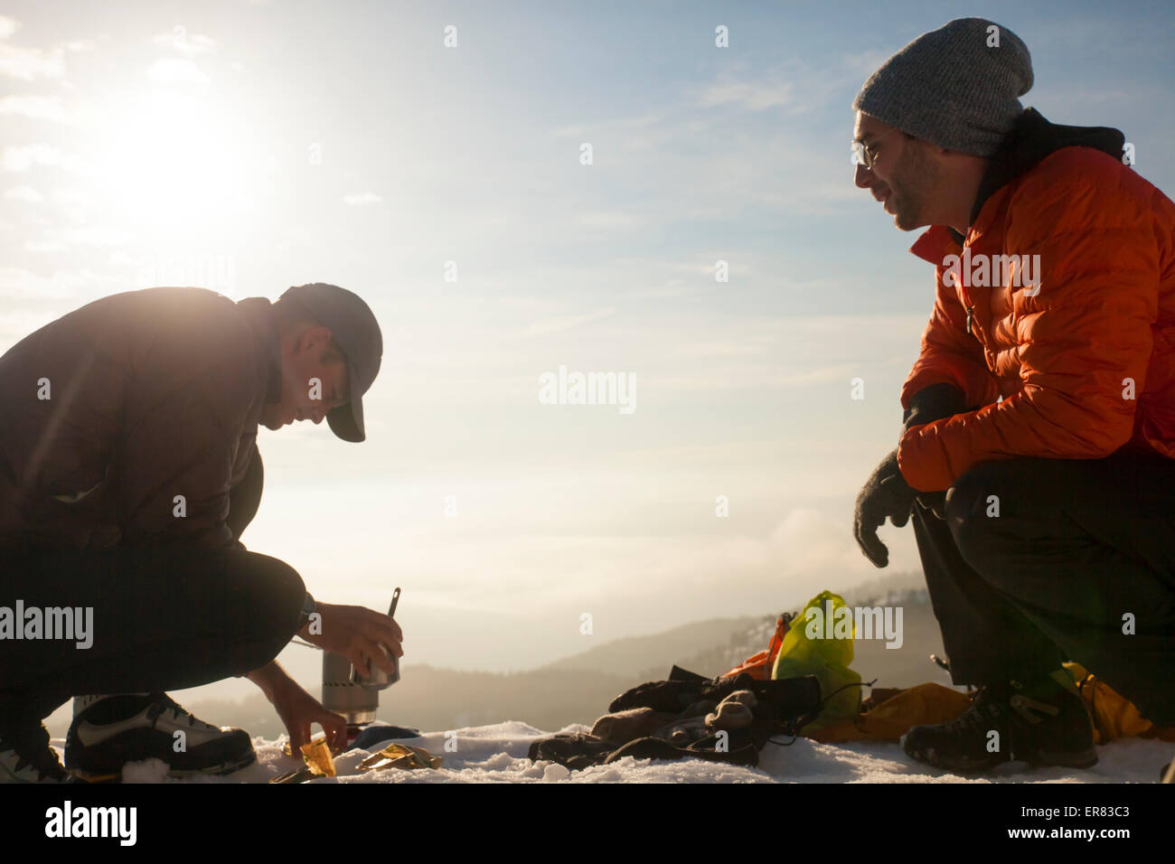 Zwei Kletterer unterhalten beim Kochen Frühstück in den Bergen. Stockfoto