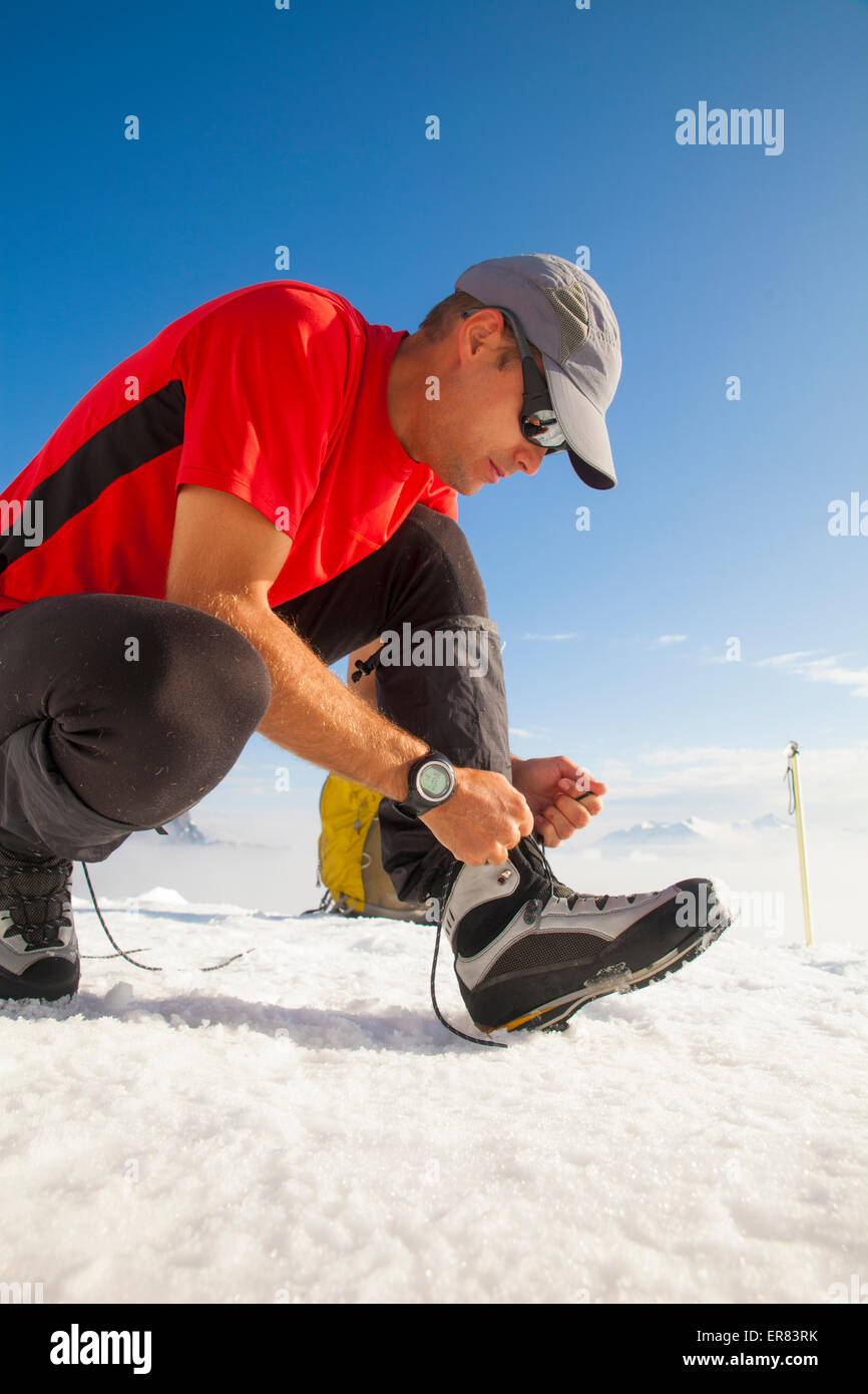 Ein Bergsteiger bindet seinen Bergsteigen Stiefel vor in Richtung Gipfel des Trios. Stockfoto