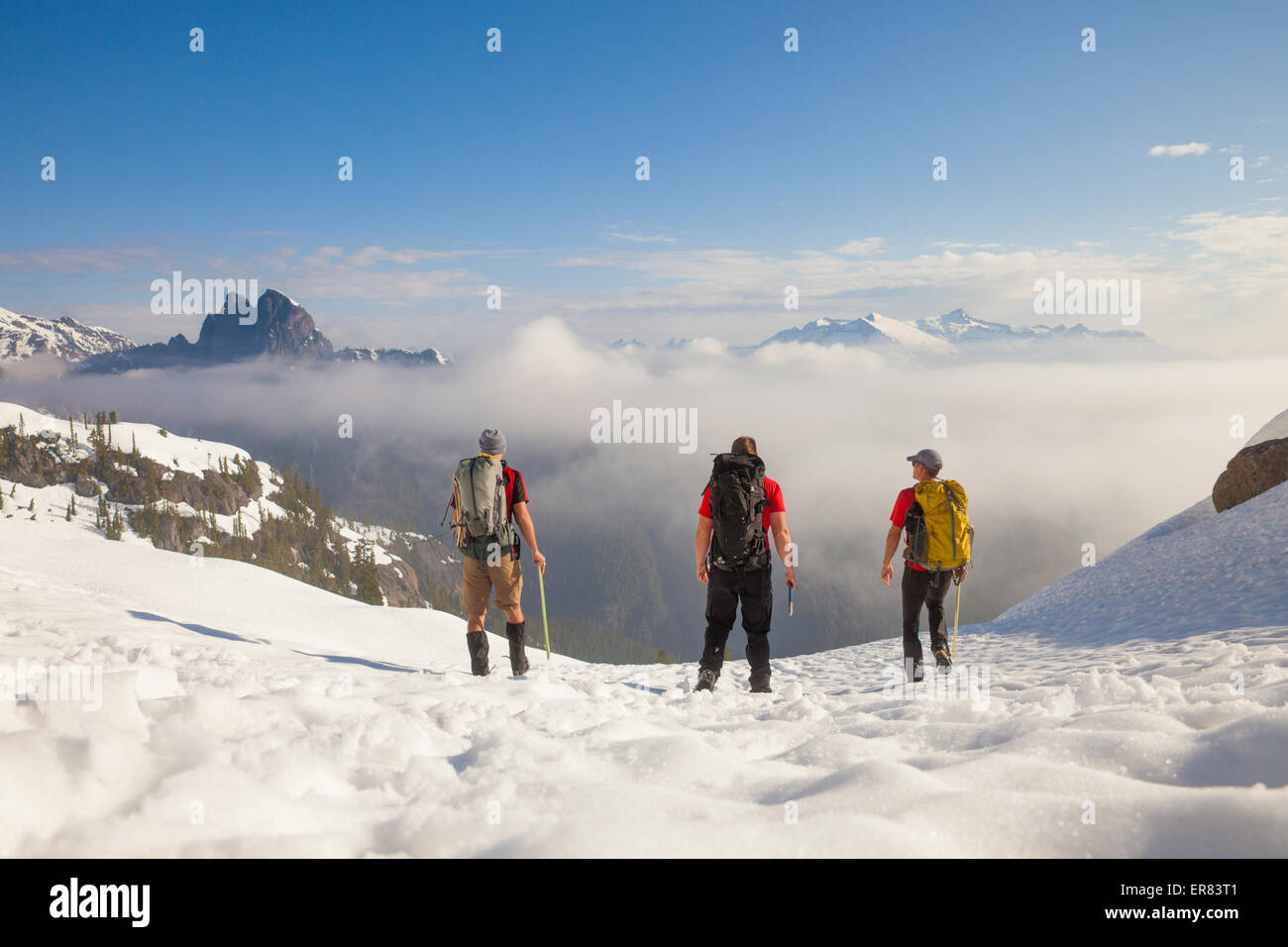 Drei Rucksacktouristen überqueren ein Schneefeld nach einer Reise in die Berge. Stockfoto