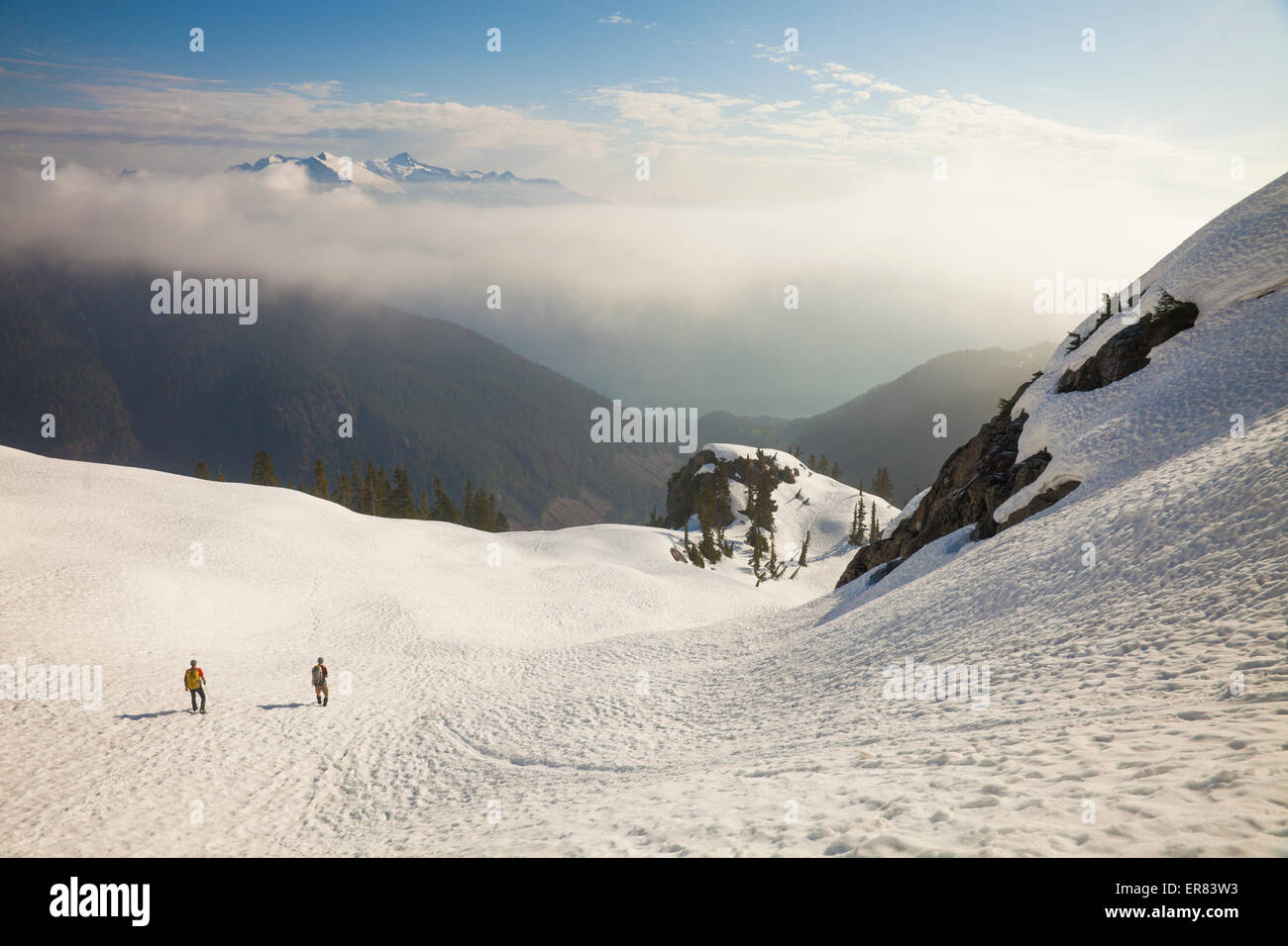 Zwei Bergsteiger steigen ein Schneefeld nach einem Ausflug in die Berge. Stockfoto