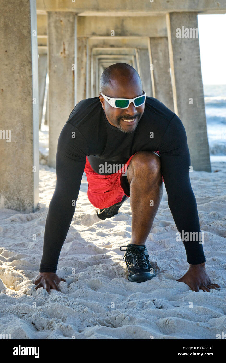 Mann unter einem Steg am Strand Stockfoto