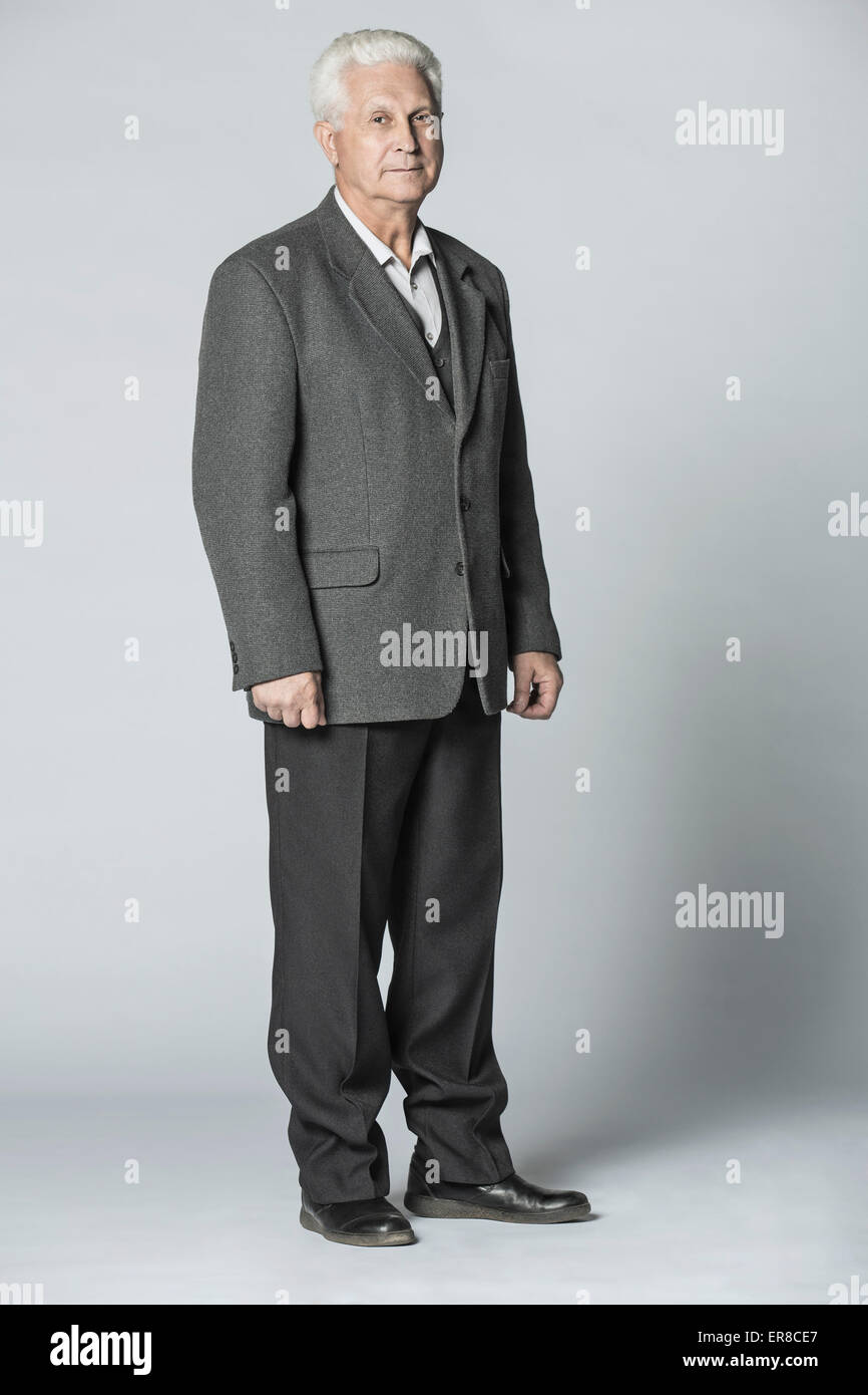 In voller Länge Portrait von zuversichtlich senior Mann stehend über grauen Hintergrund Stockfoto