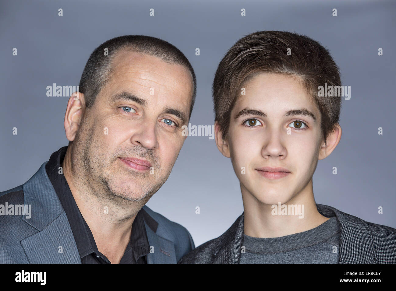 Porträt der zuversichtlich Vater mit Sohn auf grauem Hintergrund Stockfoto