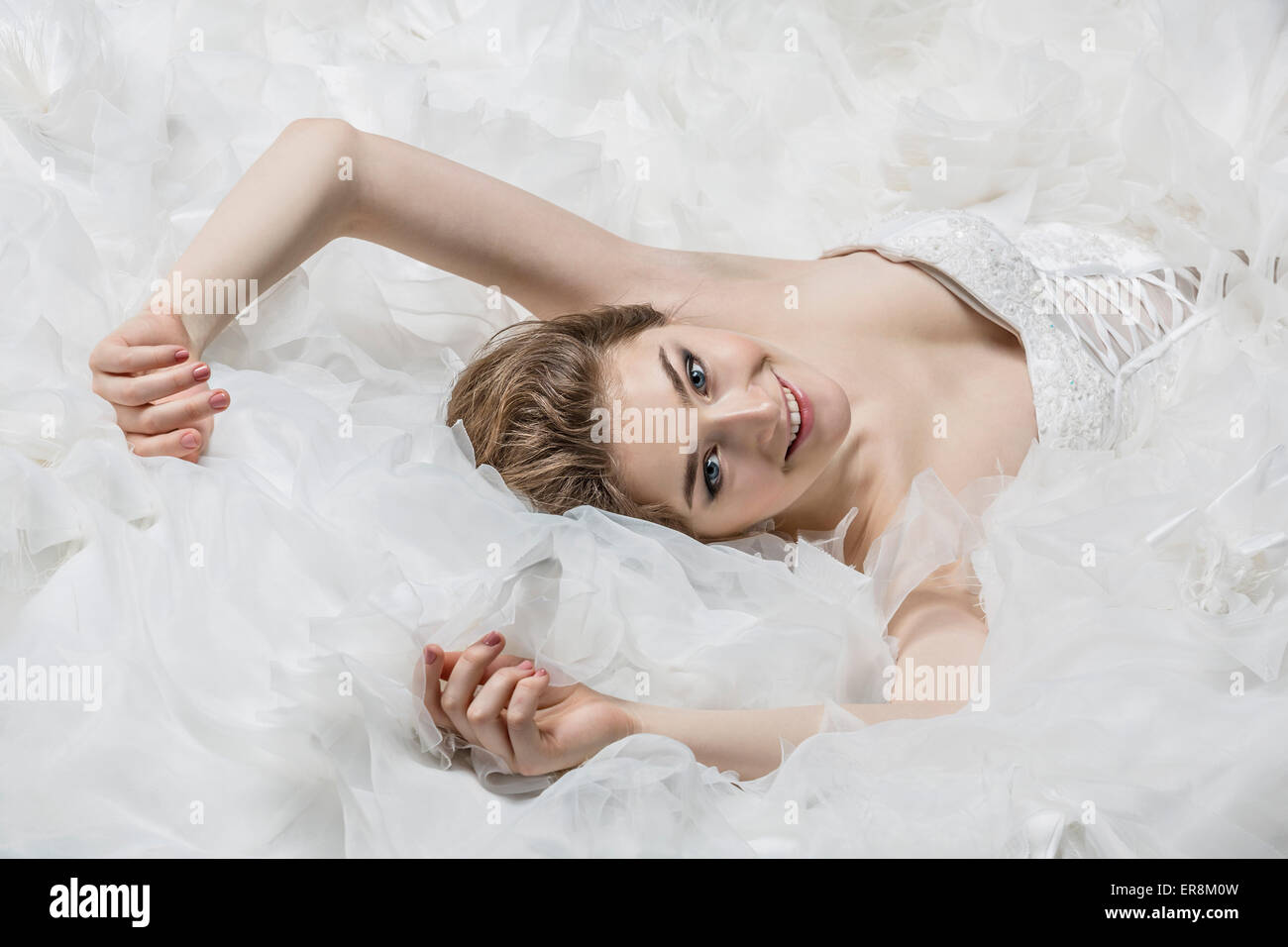 Porträt der lächelnde junge Braut im Hochzeitskleid liegend Stockfoto