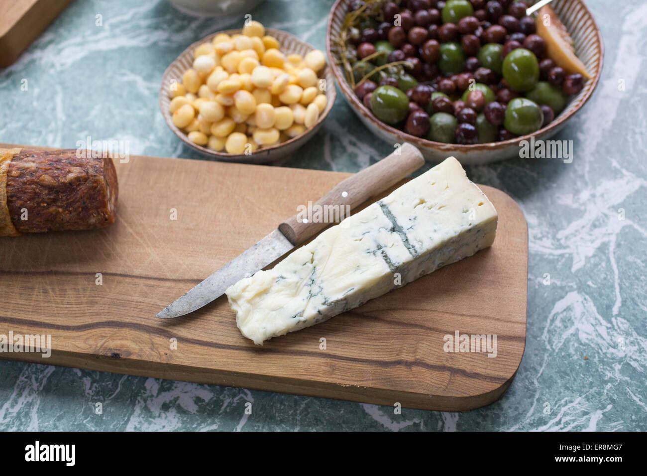 Scheibe Käse mit Oliven und Sweetcorns in der Küche Stockfoto