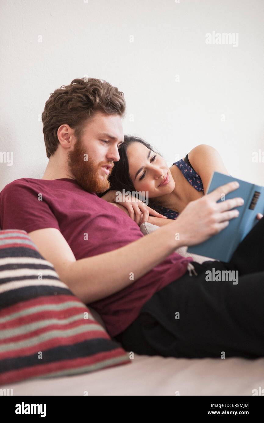 Junger Mann Lesebuch für Frau im Bett Stockfoto