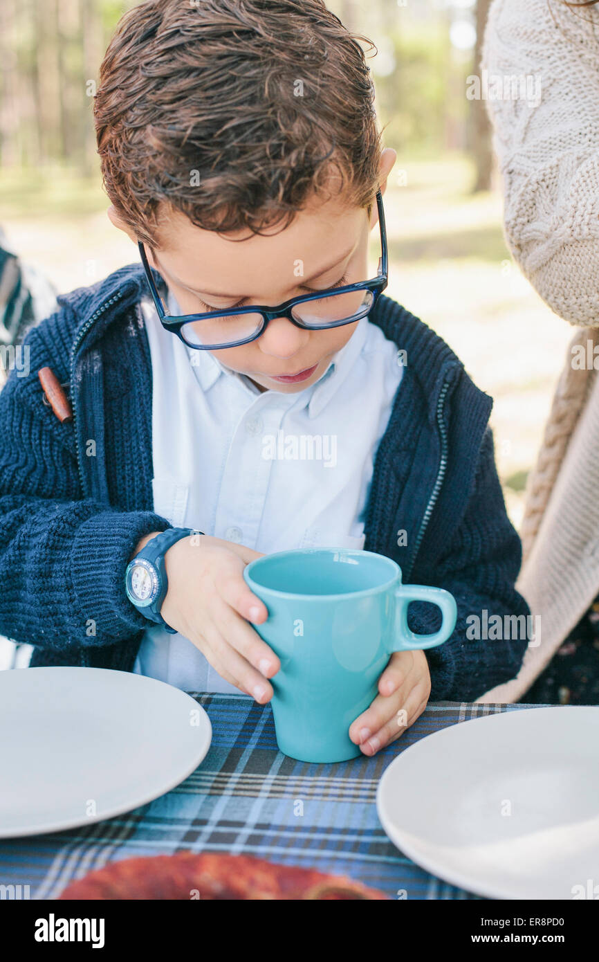 Junge hält die Kaffeetasse am Tisch im Wald Stockfoto