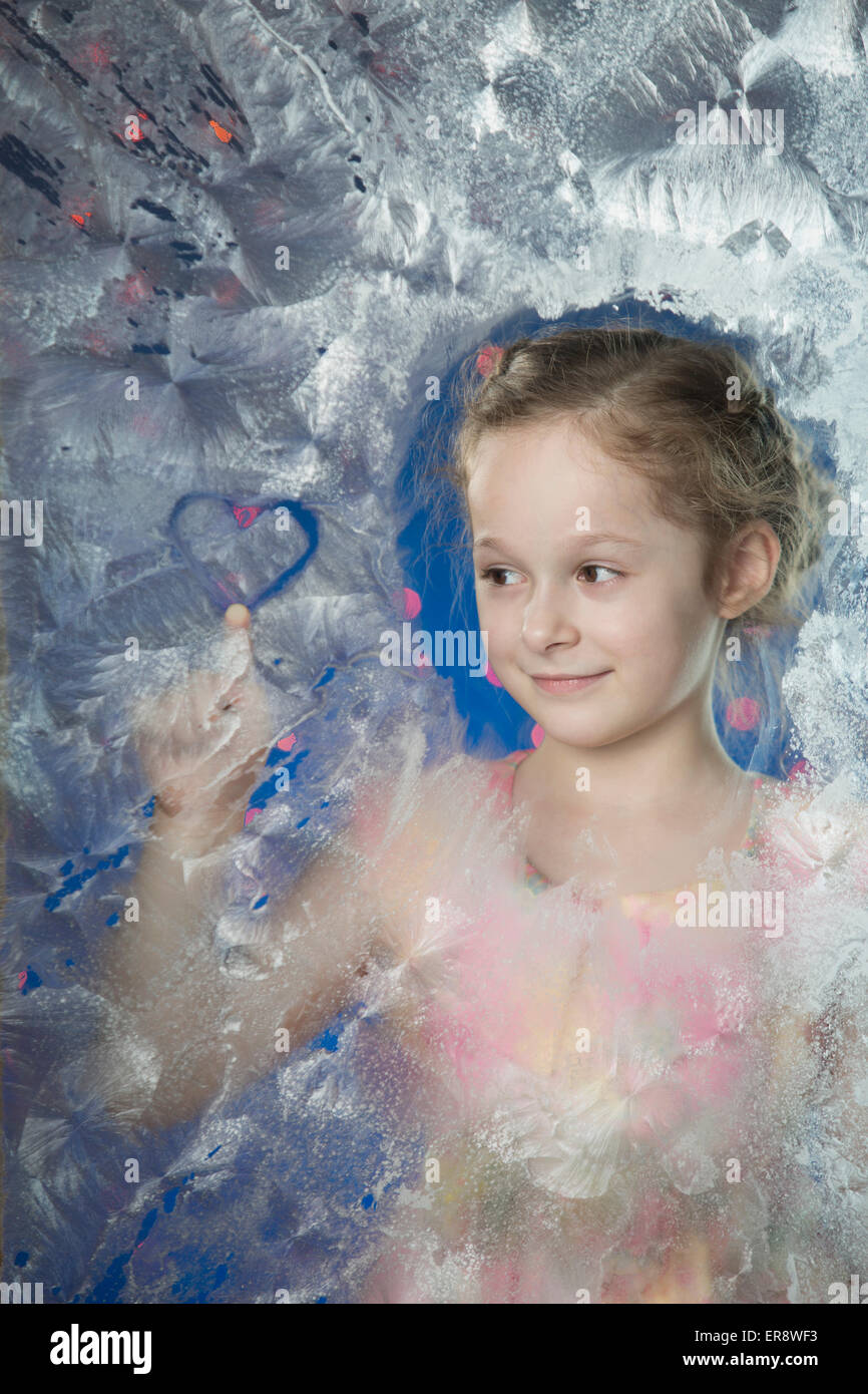Lächelndes Mädchen machen Herzform auf gefrorenem Glas Stockfoto