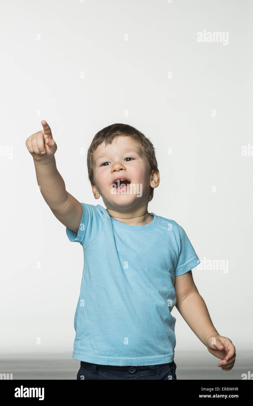 Fröhlicher Junge zeigt auf weißen Hintergrund Stockfoto