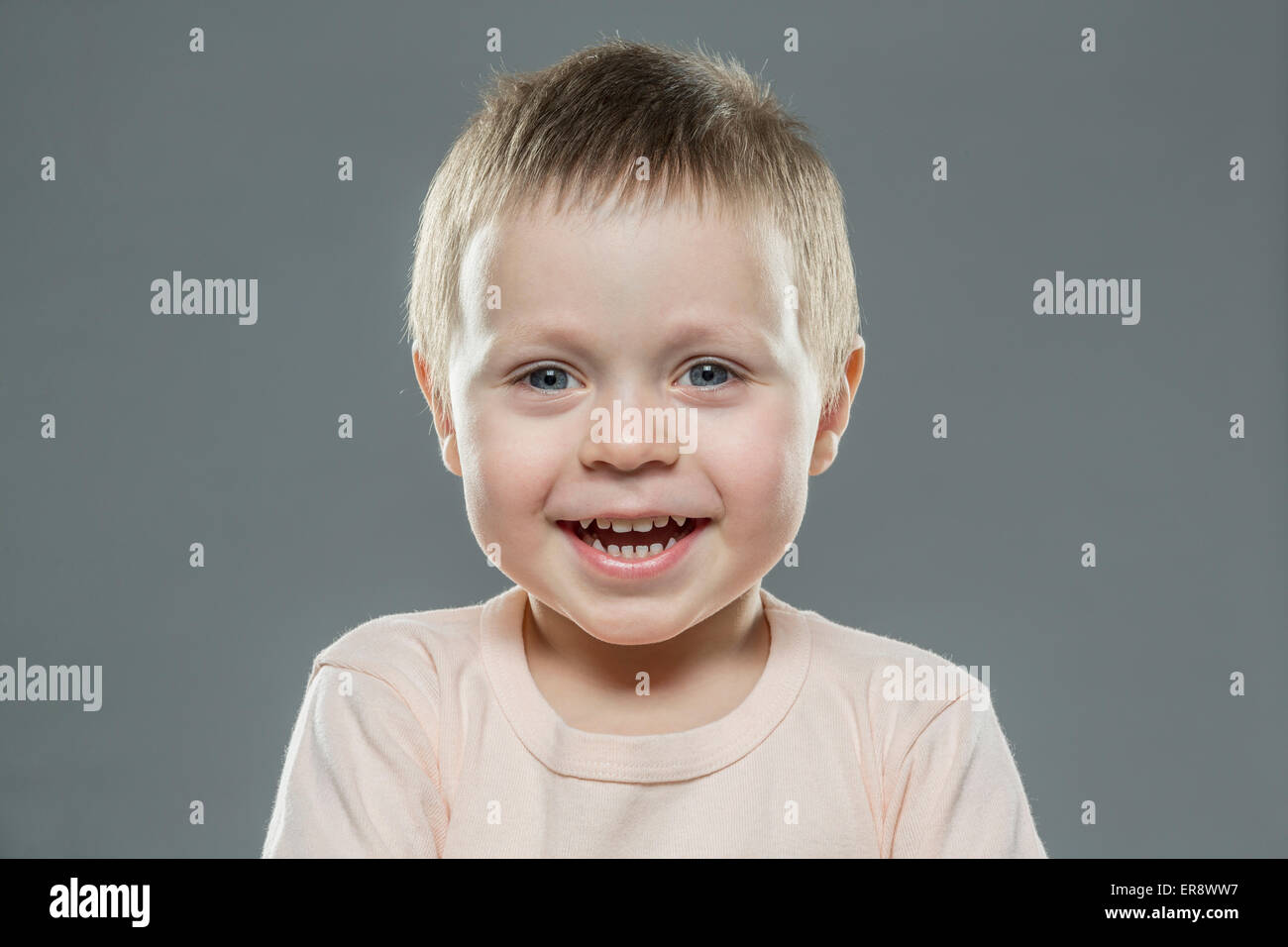Porträt von fröhlicher Junge vor grauem Hintergrund Stockfoto