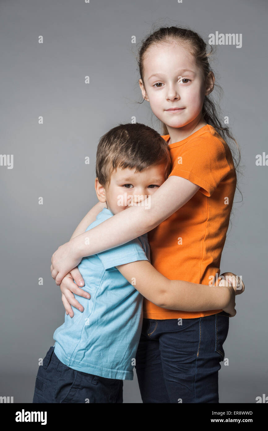 Porträt von niedlichen Geschwister umarmen vor grauem Hintergrund Stockfoto