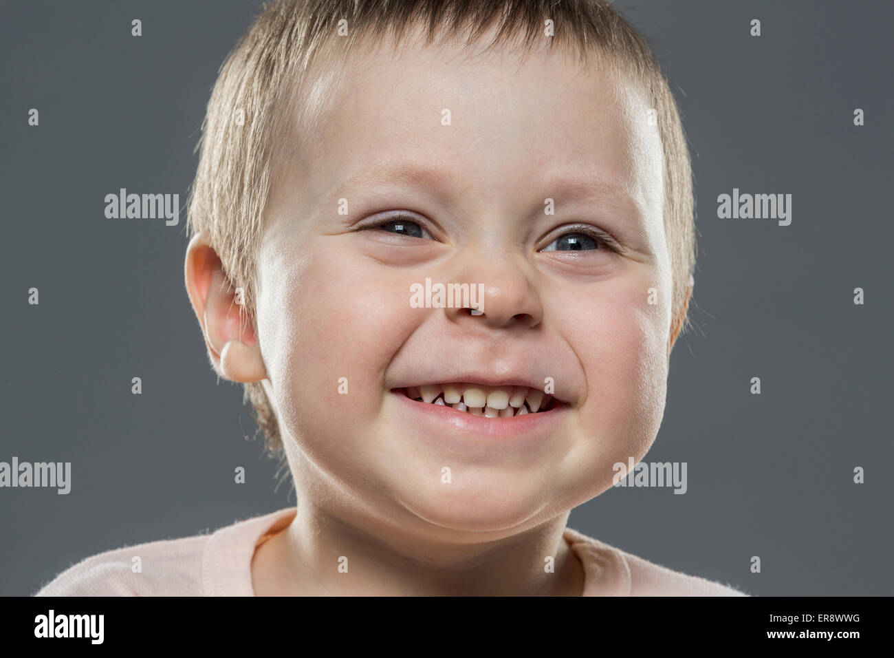 Nahaufnahme von fröhlicher Junge vor grauem Hintergrund Stockfoto