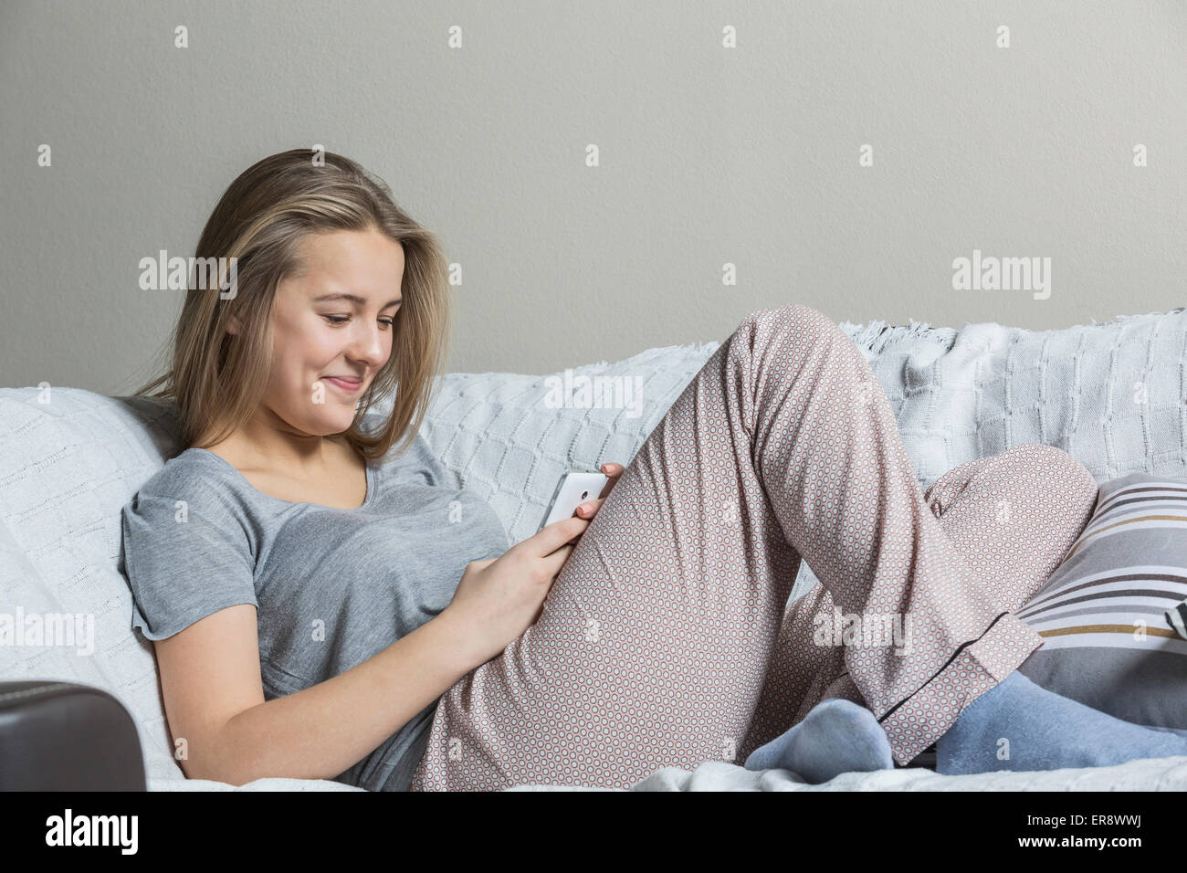 Lächelnde Teenager-Mädchen mit Smartphone zu Hause auf sofa Stockfoto