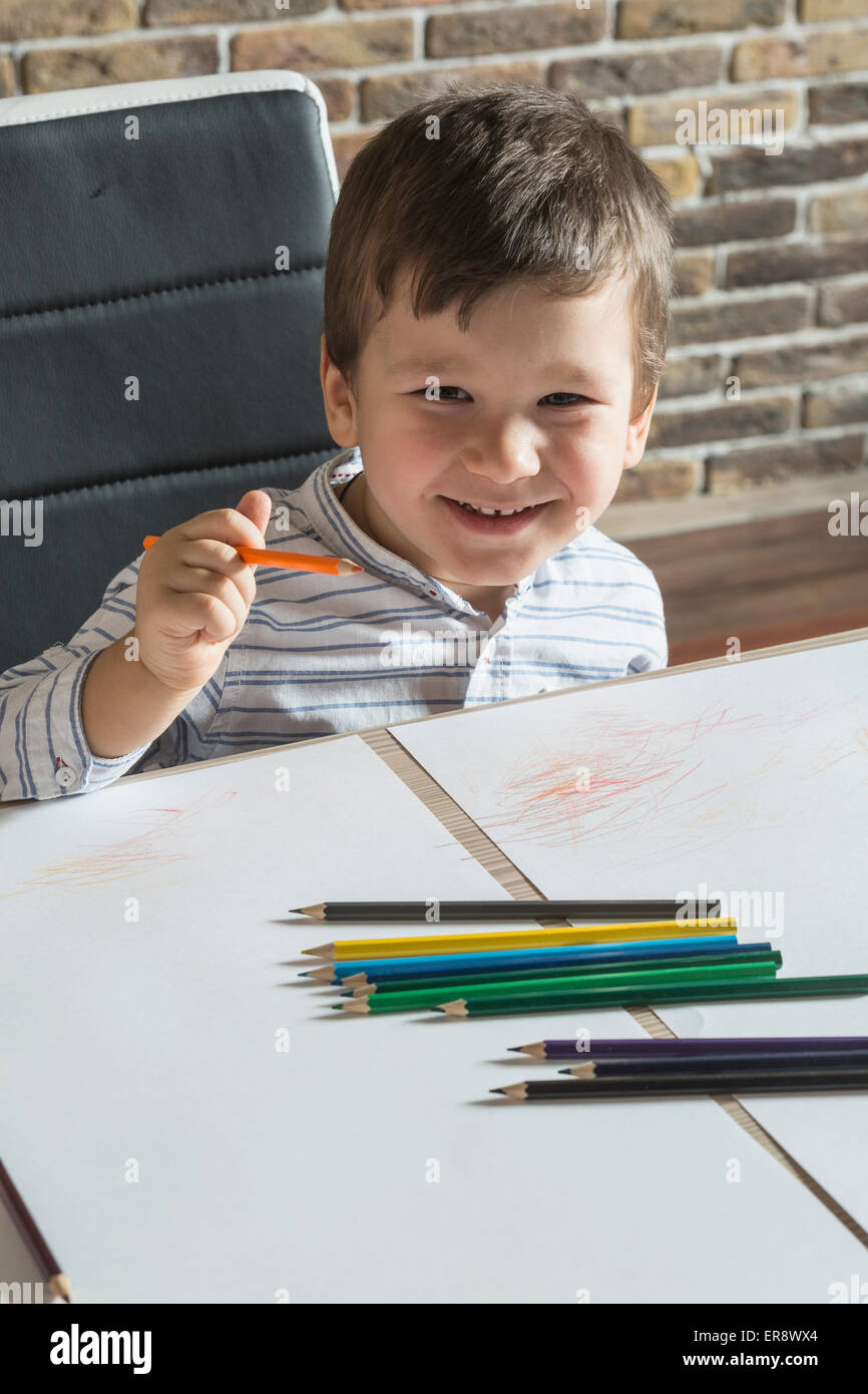 Porträt von fröhlicher Junge Zeichnung am Tisch im Haus Stockfoto