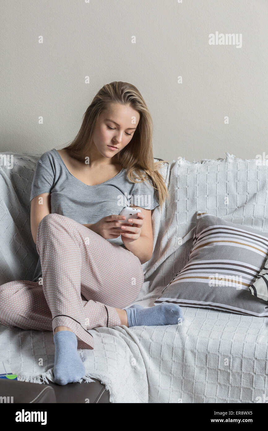 Teenager-Mädchen mit Smartphone zu Hause auf sofa Stockfoto