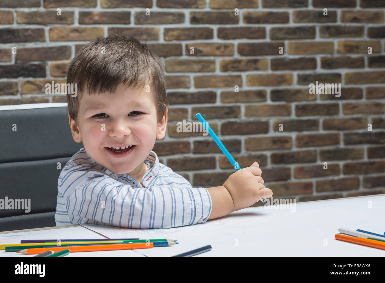 Porträt von fröhlicher Junge Zeichnung am Tisch im Haus Stockfoto