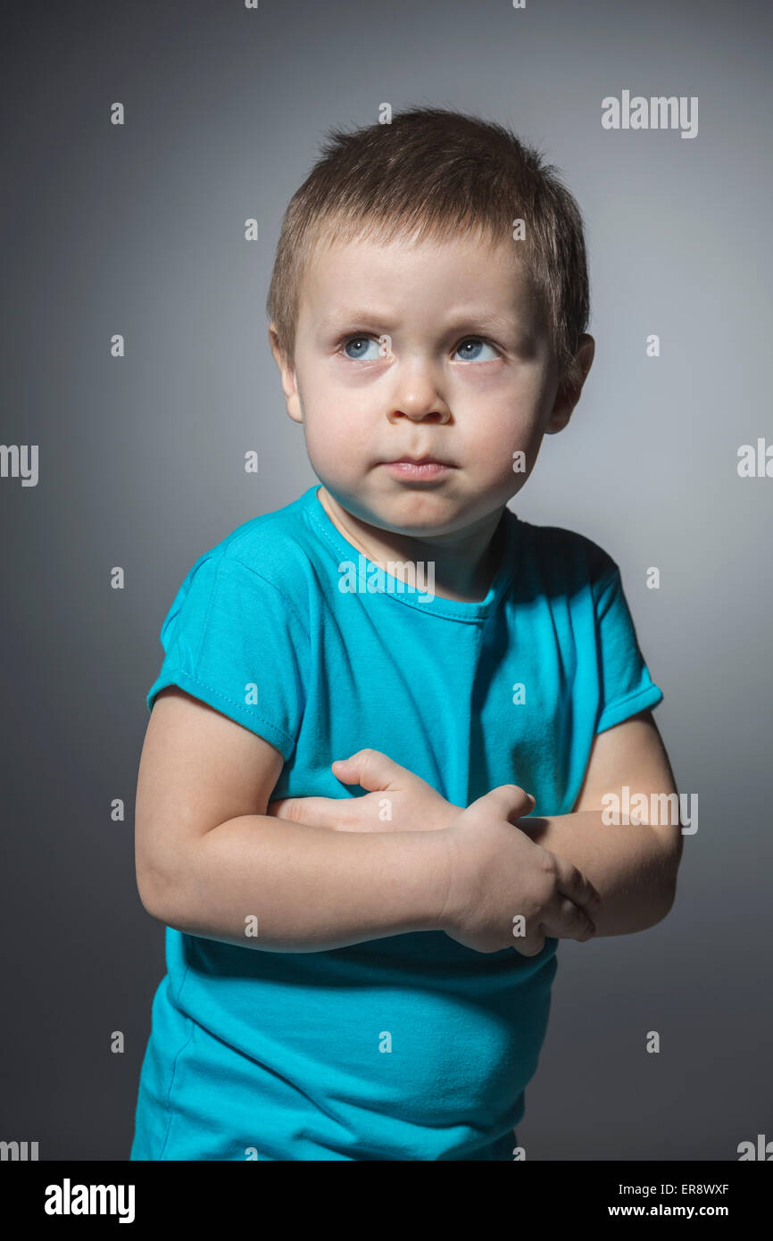 Wütende junge wegschauen während stehend Arme gekreuzt vor grauem Hintergrund Stockfoto