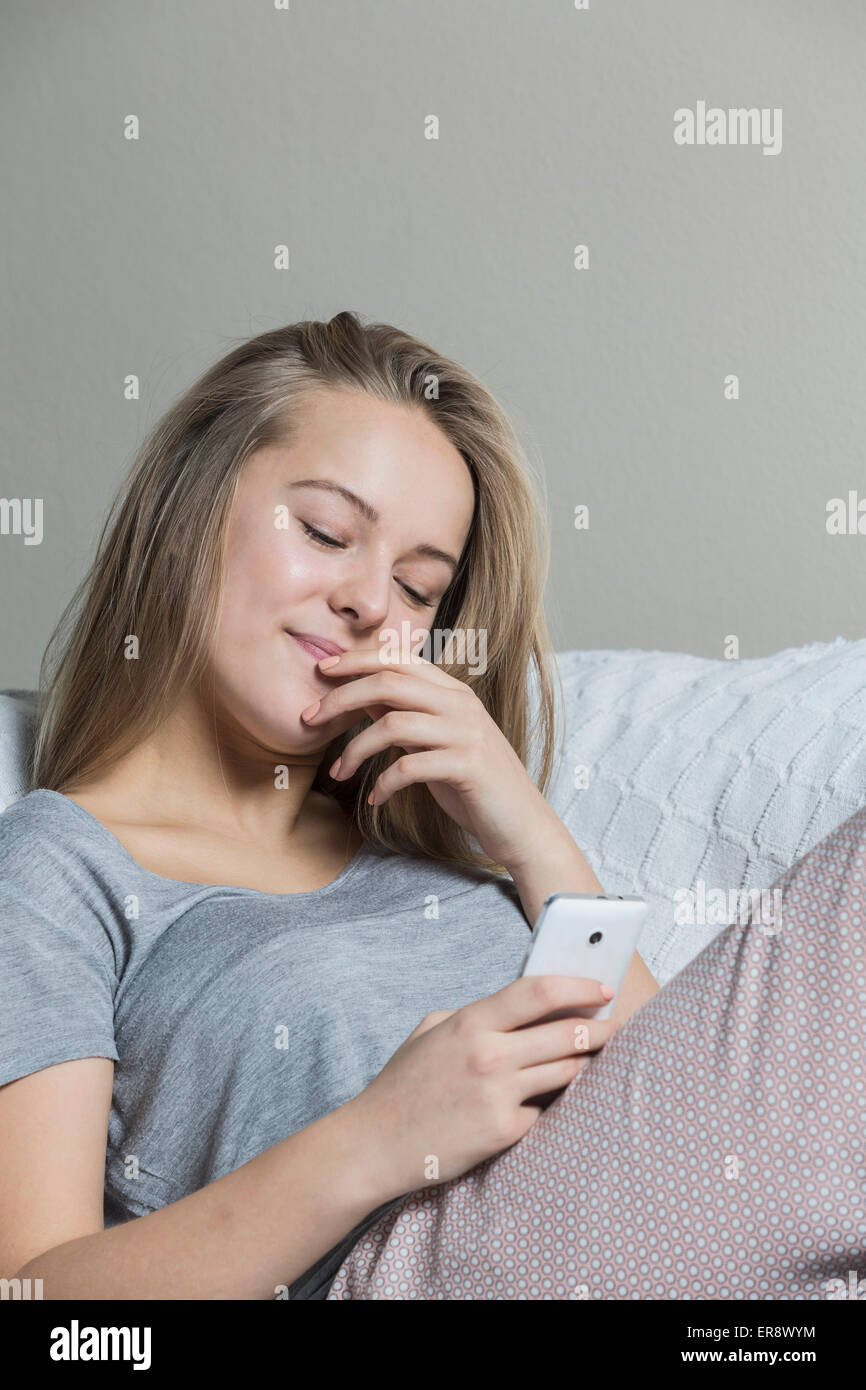 Teenager-Mädchen mit Smartphone zu Hause auf sofa Stockfoto