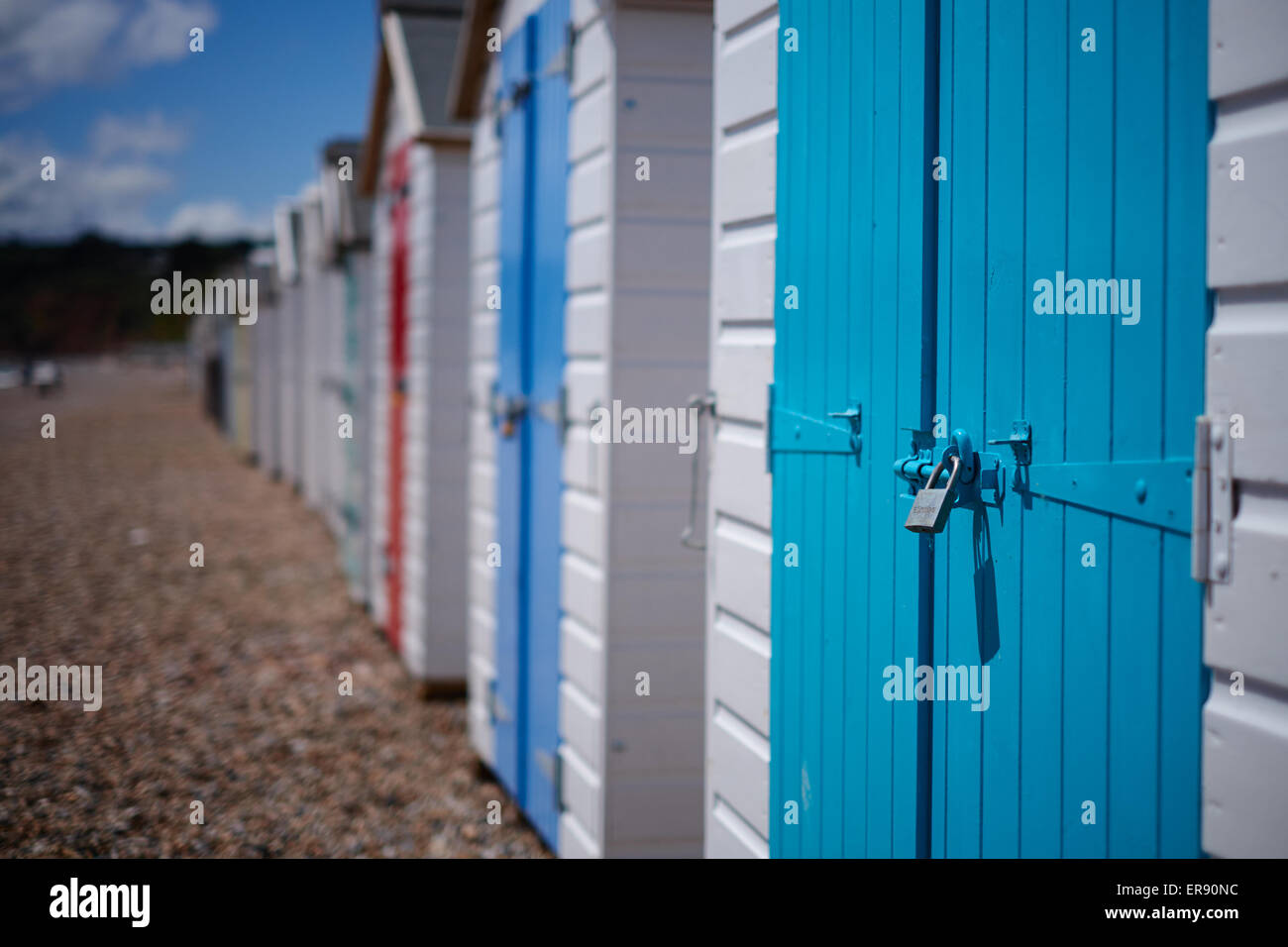 Eine Reihe von Strandhütten mit bunten Türen am Kiesstrand, Devon, UK Stockfoto