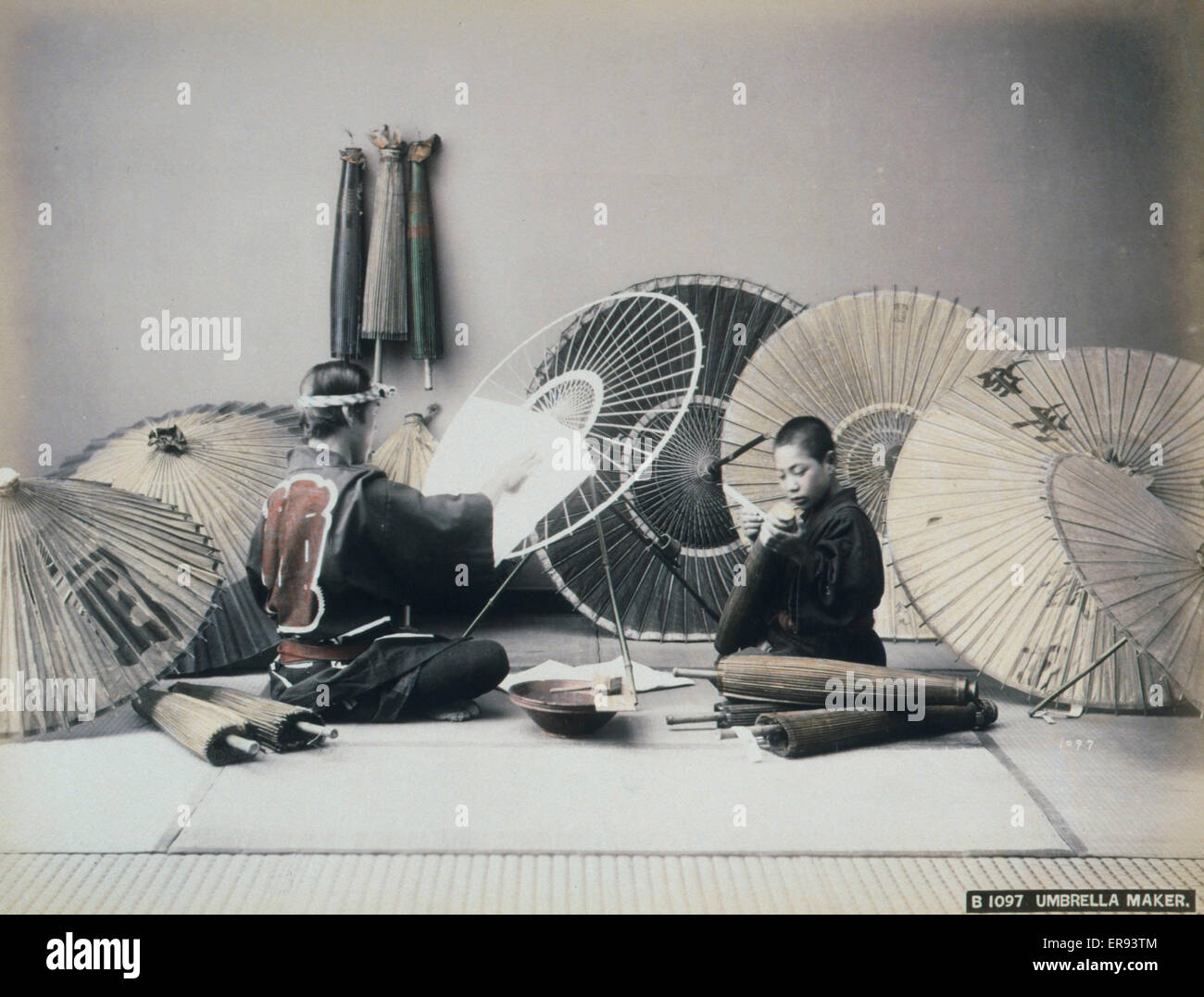 Sonnenschirm-Hersteller. Foto zeigt einen Mann und eine junge Sonnenschirme machen. Aquarelle-Zeichnungen auf dem Berg zeigen Blumen in der oberen rechten Ecke und einen Kimono Trocknung auf einen Holzrahmen in der linken unteren Ecke. Bis heute ca. 1890. Stockfoto