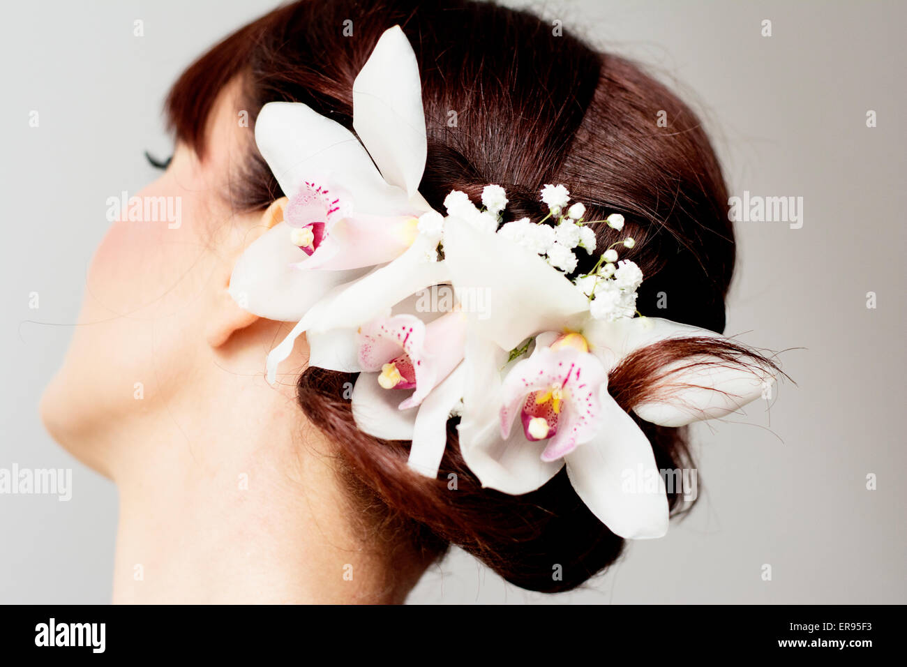 Braut posiert ihre Frisur mit Orchideen für ihren Hochzeitstag. Braut hat Pony. Stockfoto