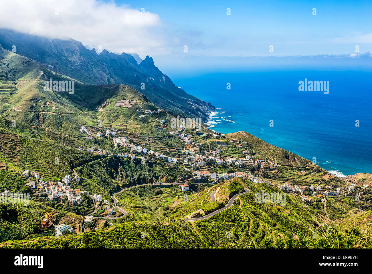 Berg und Wolken mit kleinen Stadt oder Dorf und Himmel Horizont Landschaft nahe der Atlantik Küste in Teneriffa Kanarische Stockfoto