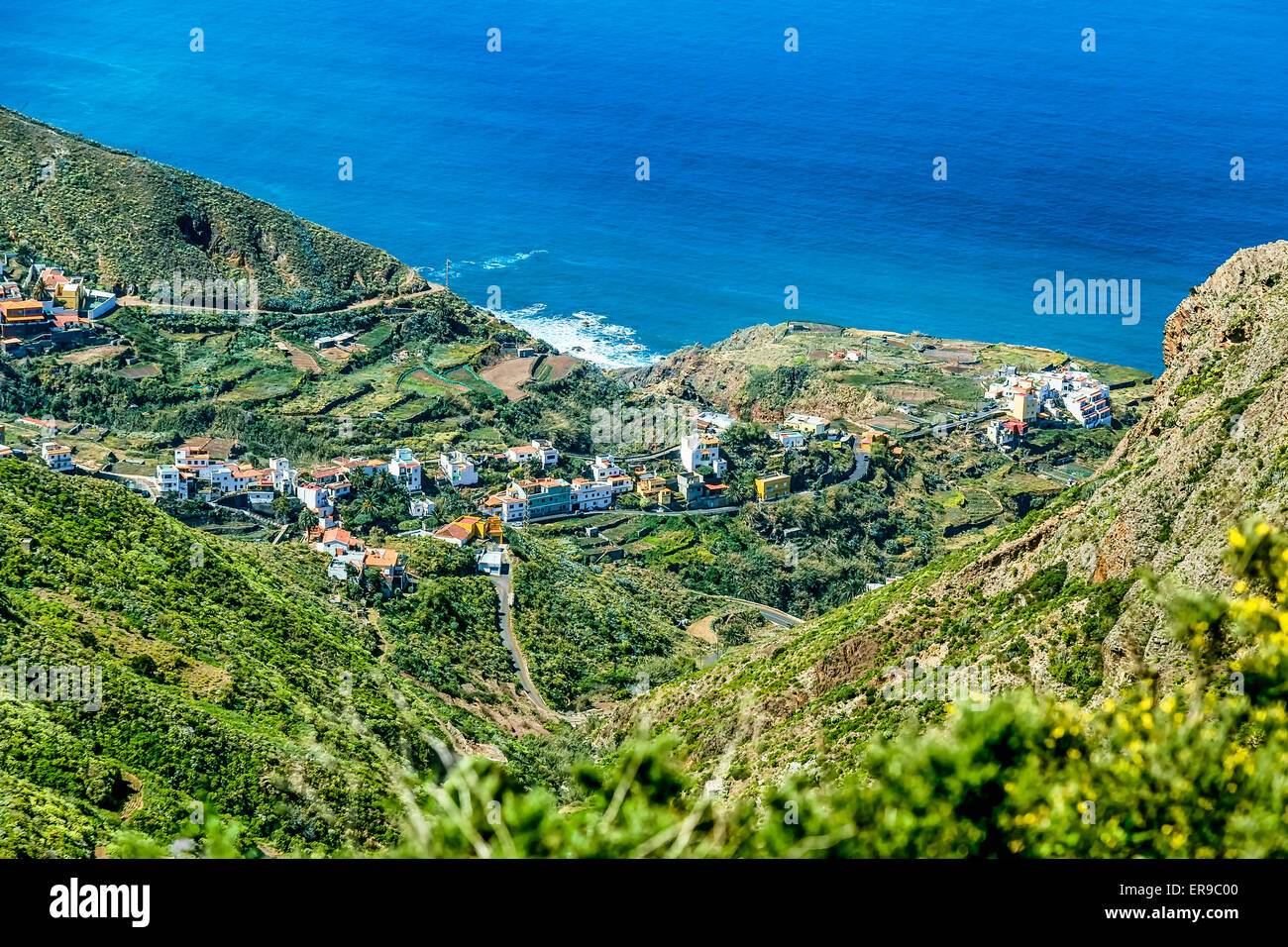 Kleine Stadt oder Dorf und Serpentine Straße im grünen Tal Berglandschaft in der Nähe der Küste oder Ufer des Atlantischen Ozeans Stockfoto